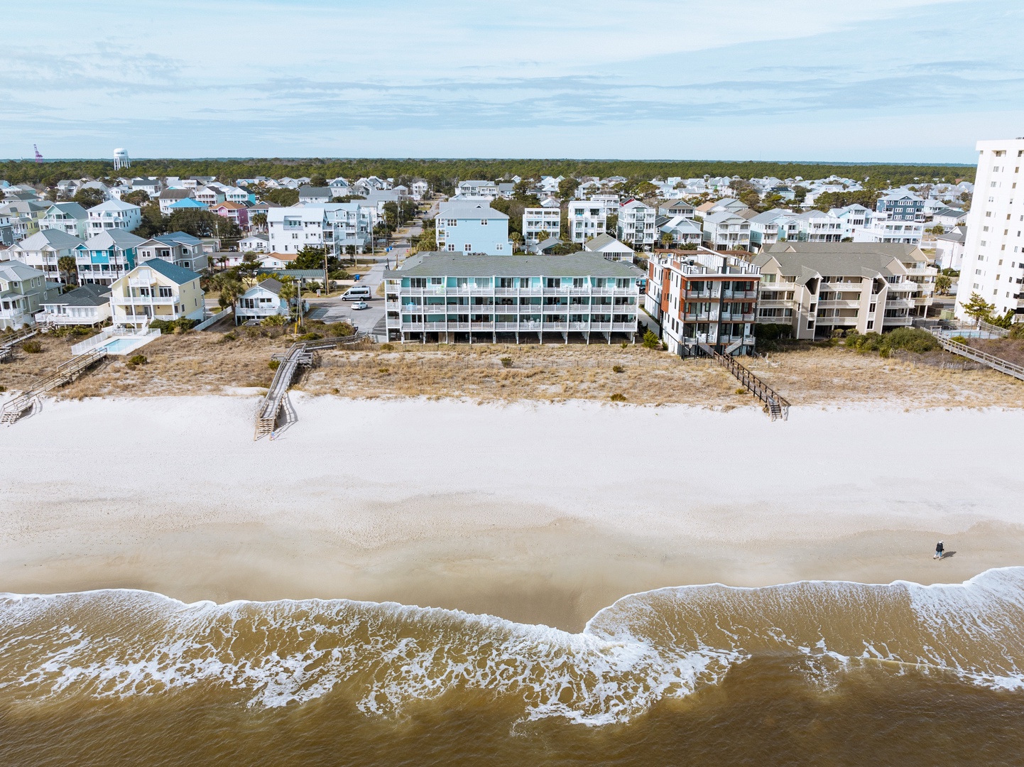 Aerial view of beachfront properties situated directly on pristine sandy shores with gentle ocean waves.