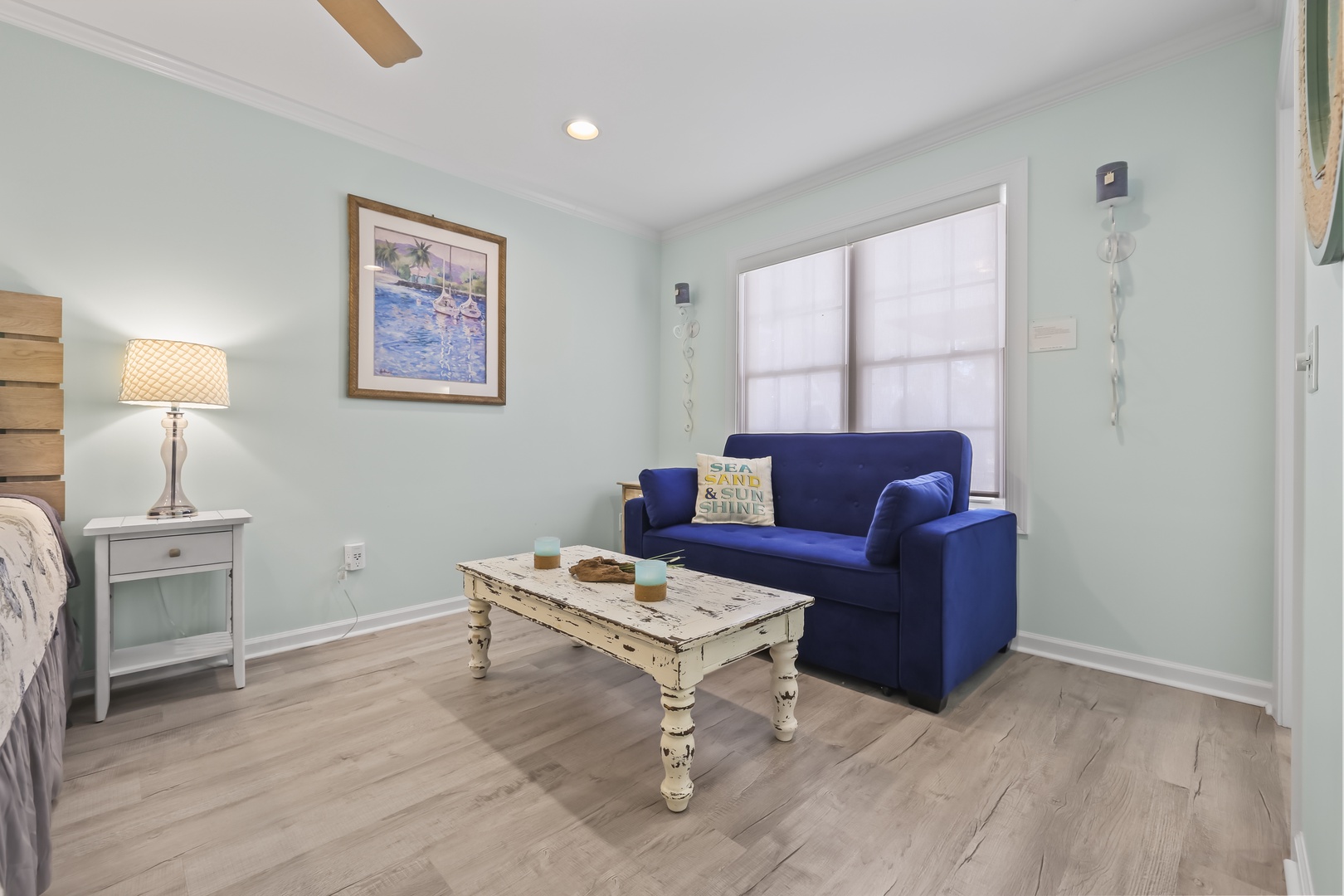 Unwind in your charming coastal retreat, where soft blue walls and a plush sofa invite relaxation. Natural light fills this cozy space, perfect for lazy mornings or evening conversations.