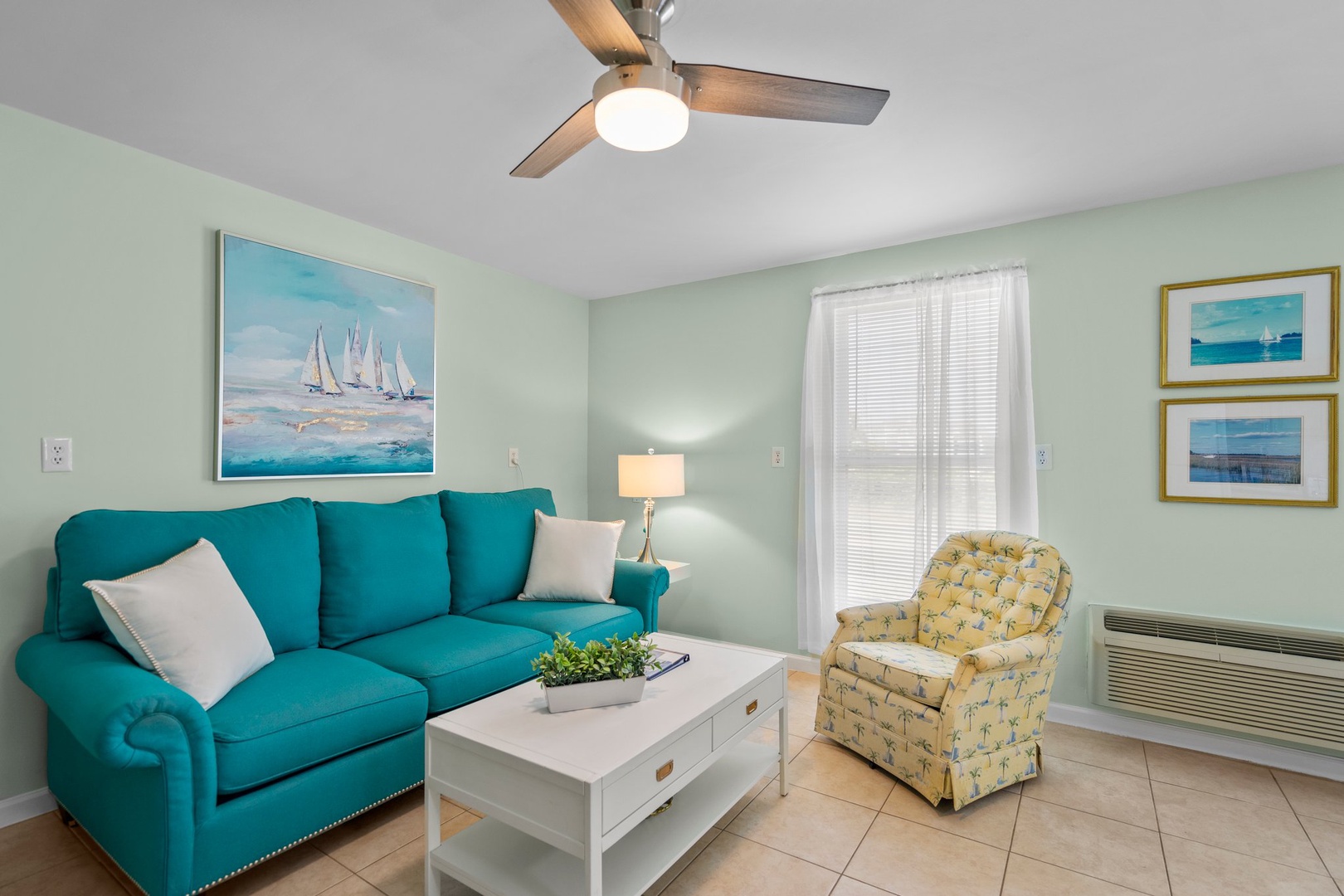 Relax in your bright living space with turquoise sectional, coastal artwork, and ceiling fan keeping you comfortable.