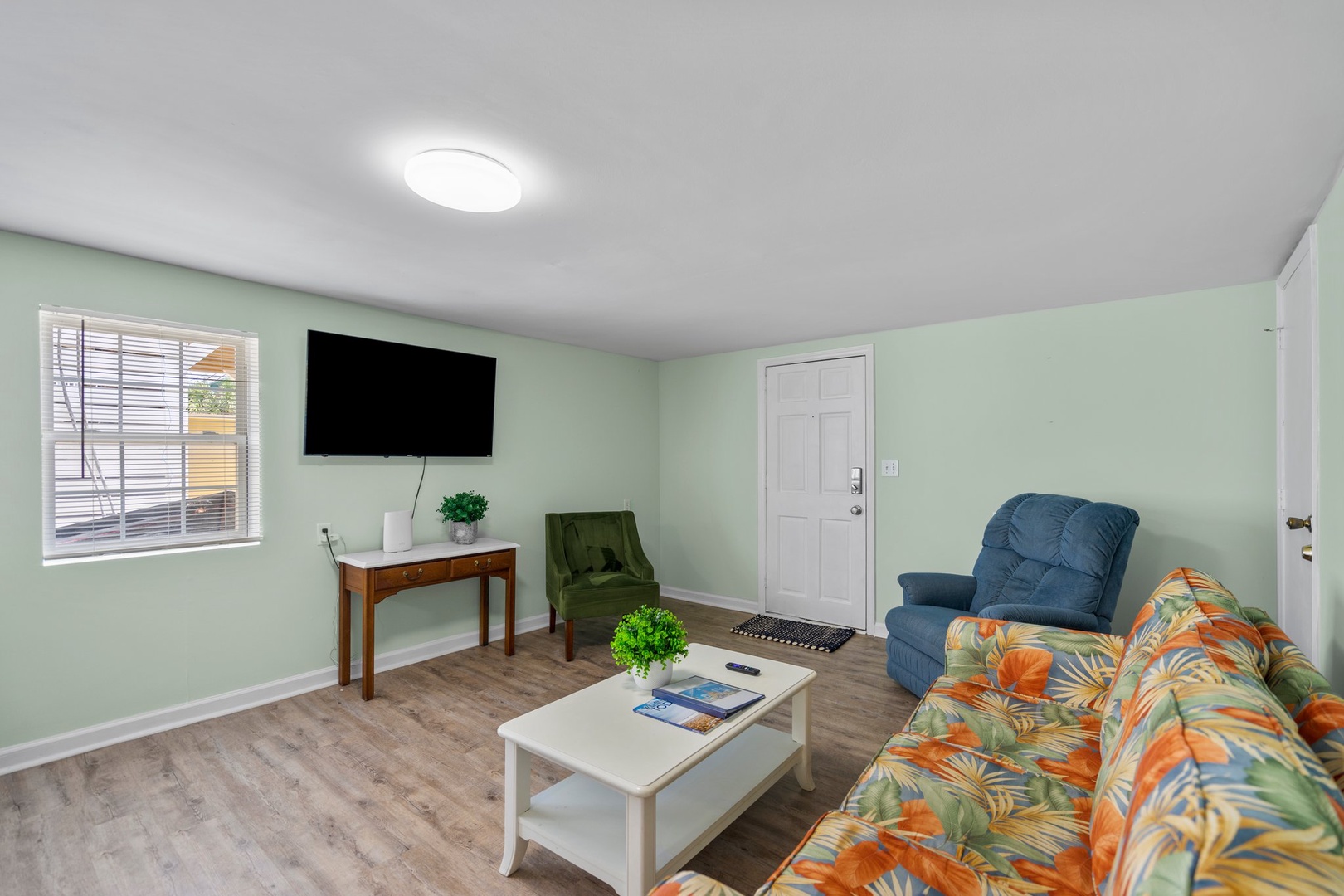 Relax in your bright living space with comfortable seating, wall-mounted TV, and tropical-themed furnishings that create a welcoming home away from home.
