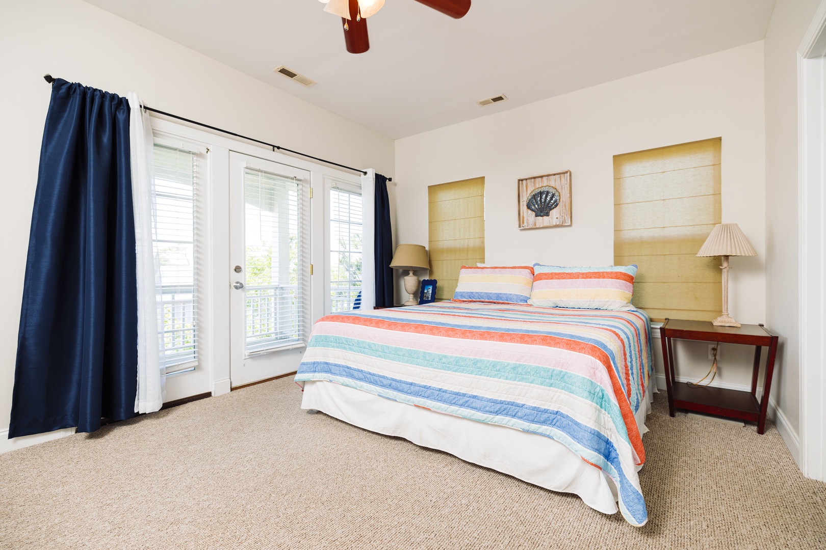Drift off to sleep in your coastal retreat with cheerful striped bedding and natural light streaming through French doors.