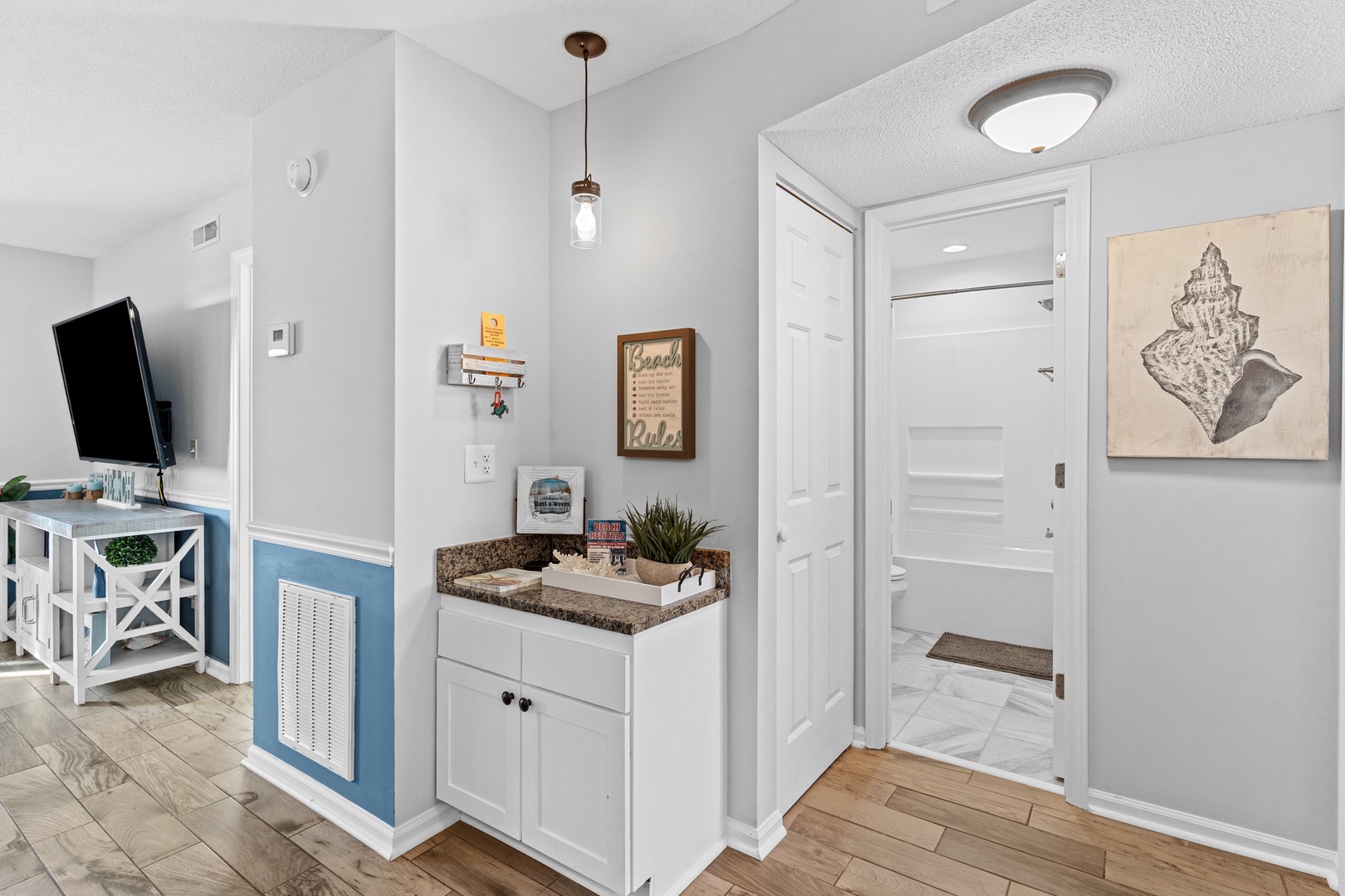 Your welcoming entry opens to coastal-inspired living with warm wood floors, thoughtful storage, and beach artwork setting the tone for relaxation.