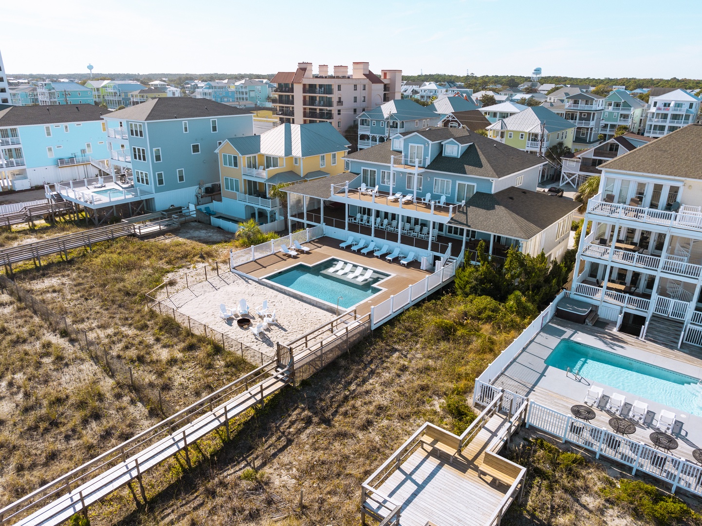 Aerial view showcasing beachside vacation homes with private pools and coastal community surroundings.