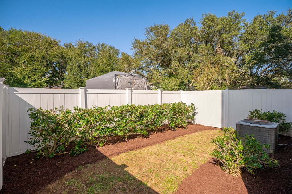 Private backyard features manicured landscaping with established shrubs, fresh mulch, and mature trees creating a peaceful outdoor retreat for relaxation.