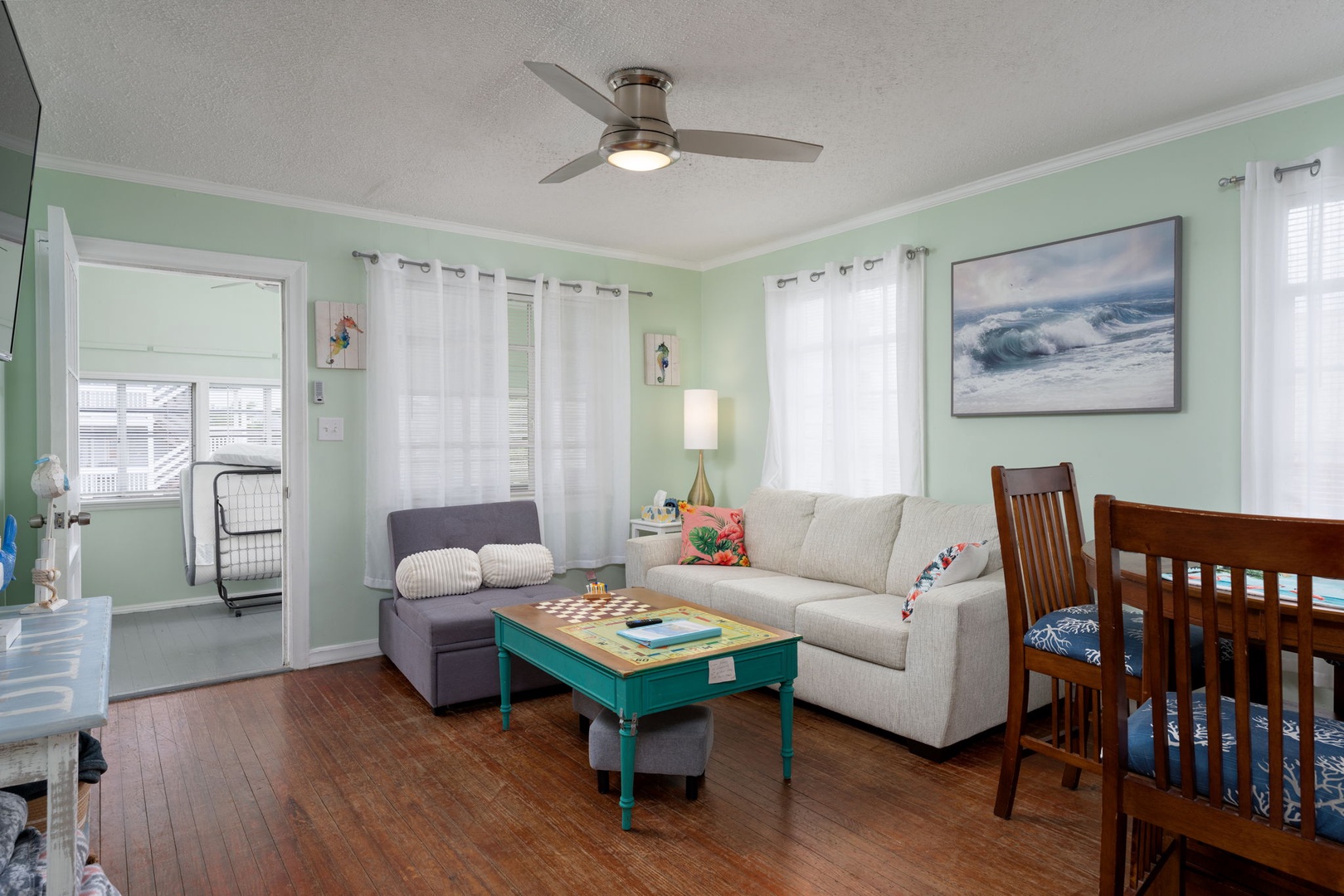 Unwind in your coastal-themed living room with soft mint walls, cozy sectional sofa, and ocean artwork creating a peaceful retreat.