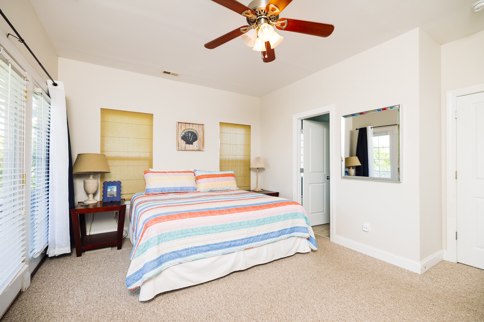 Relax in your bright, cheerful bedroom with colorful striped bedding and cooling ceiling fan for comfortable nights.