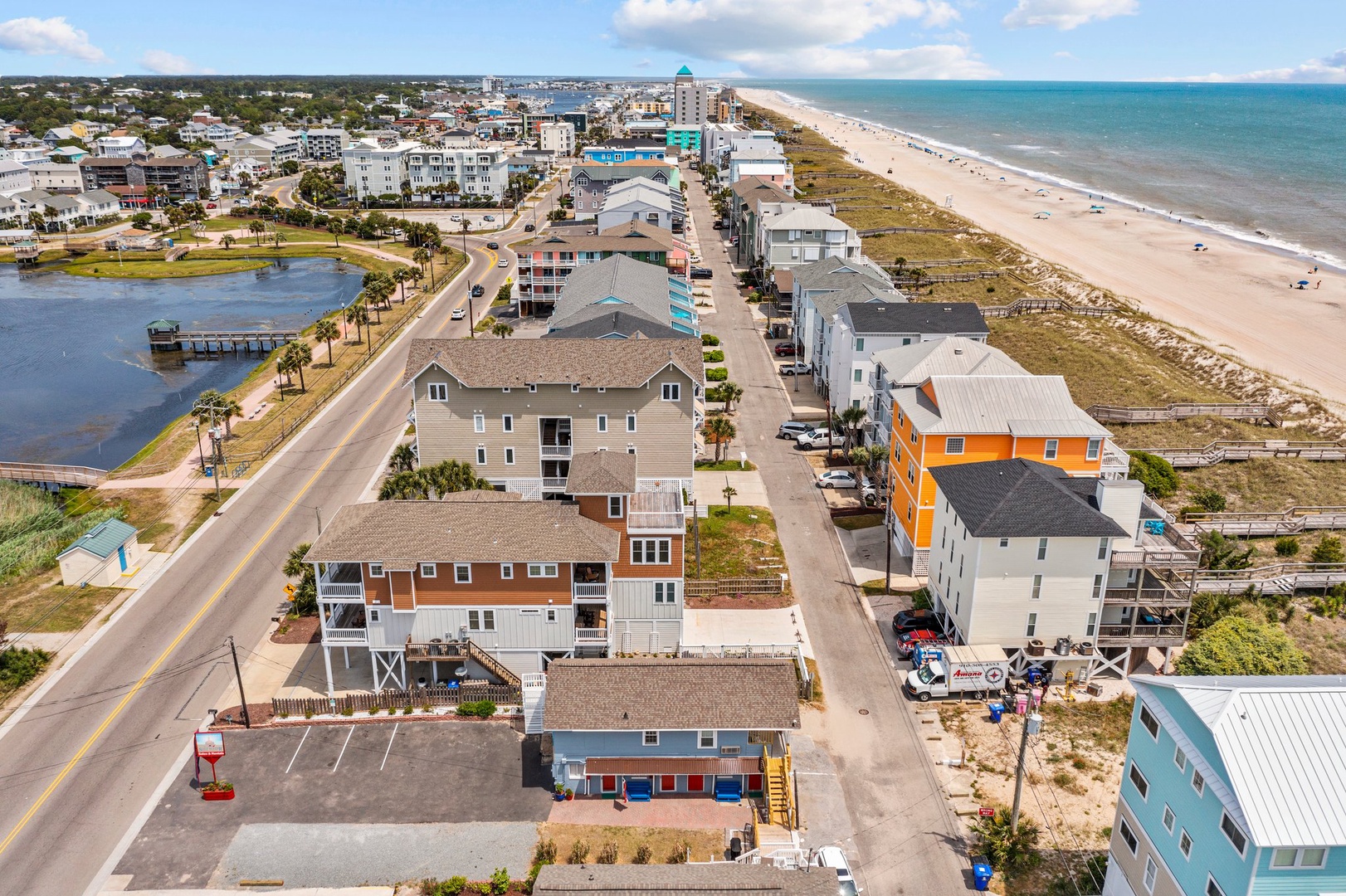 Coastal town with colorful vacation homes along pristine sandy beach and scenic waterway views.