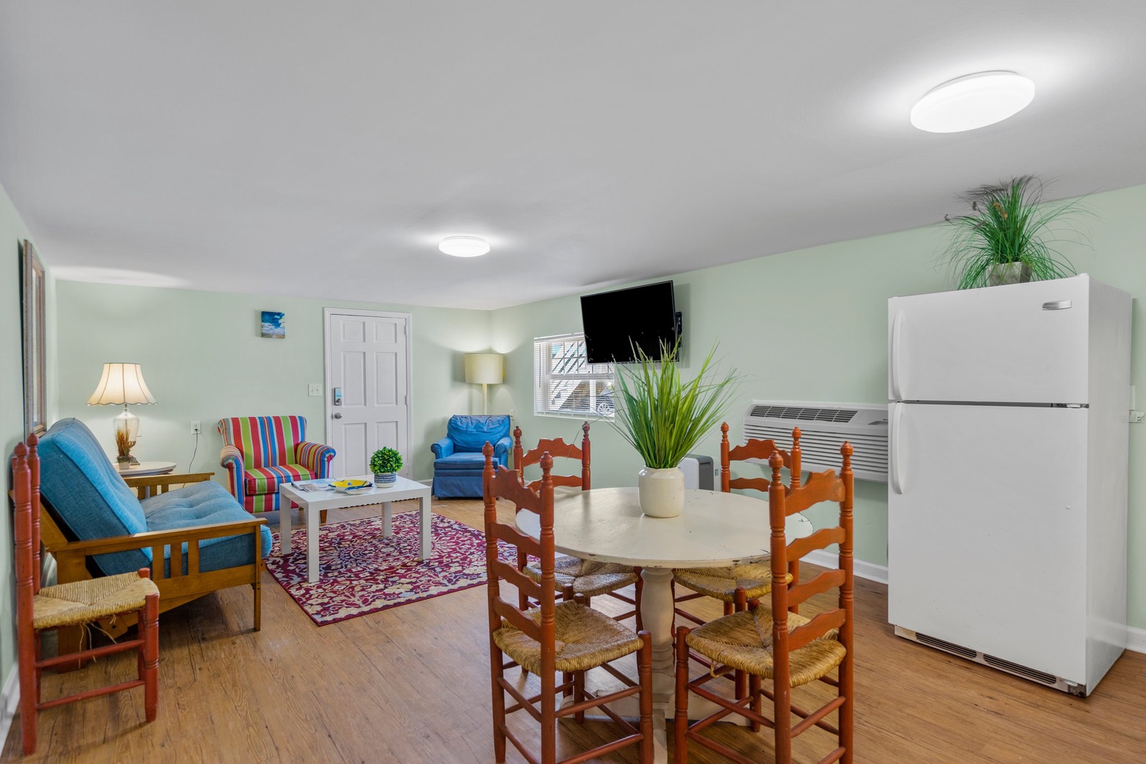 Your bright open-plan space combines living and dining seamlessly, with colorful seating, a flat-screen TV, and full-size fridge for comfortable self-catering stays.