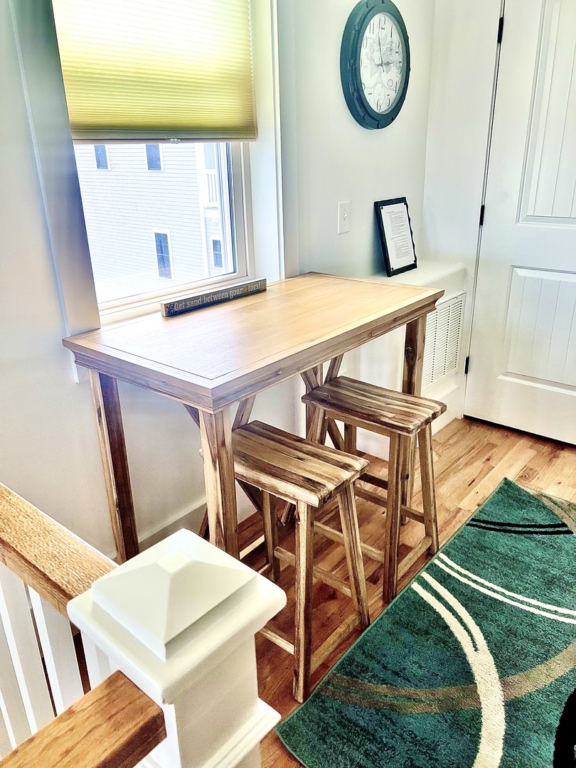 Your bright workspace awaits with a wooden desk and stools, perfect for morning coffee or planning your day's adventures.
