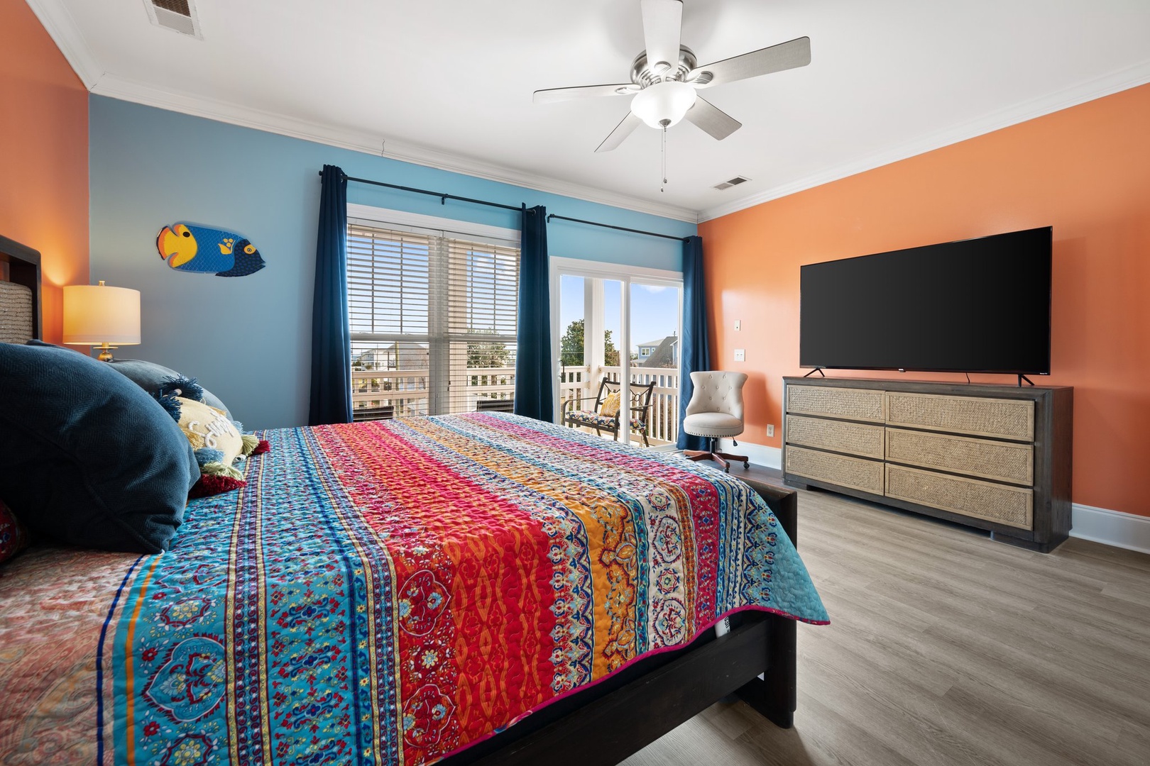 Drift off in your vibrant bedroom with colorful bedding, ocean breezes through your balcony doors, and a large TV for cozy evenings.