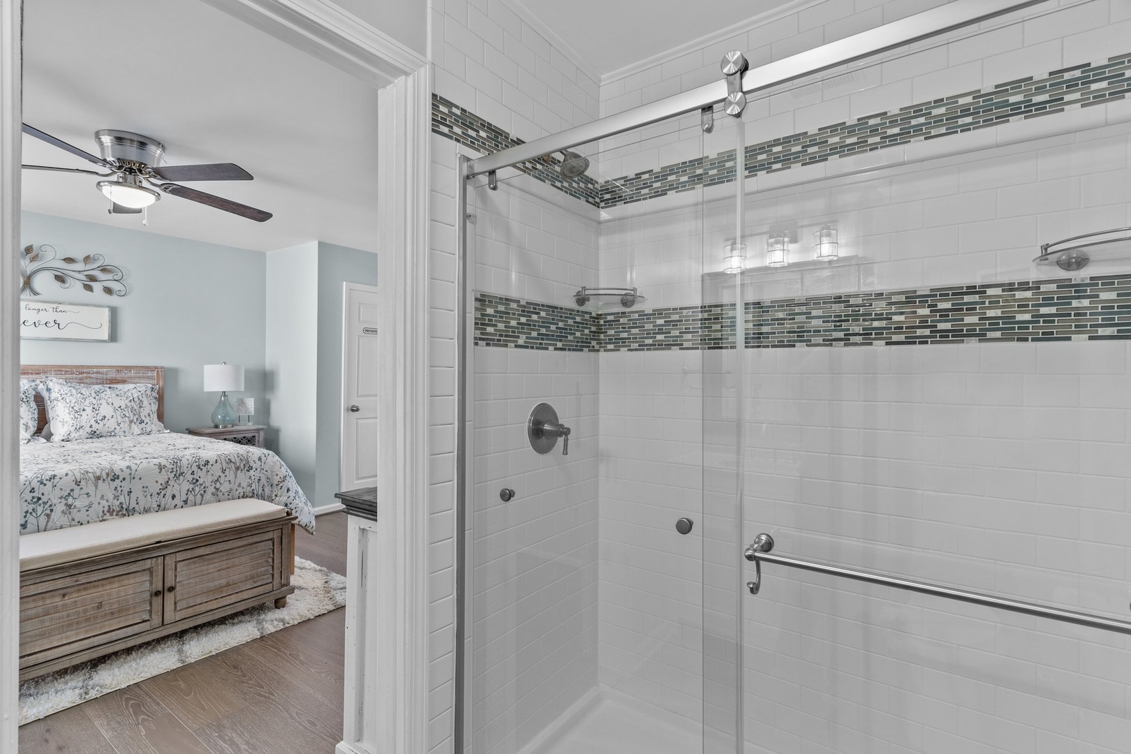 Step into your spa-like ensuite with elegant glass shower and calming blue mosaic accents, perfectly complementing your peaceful bedroom retreat.