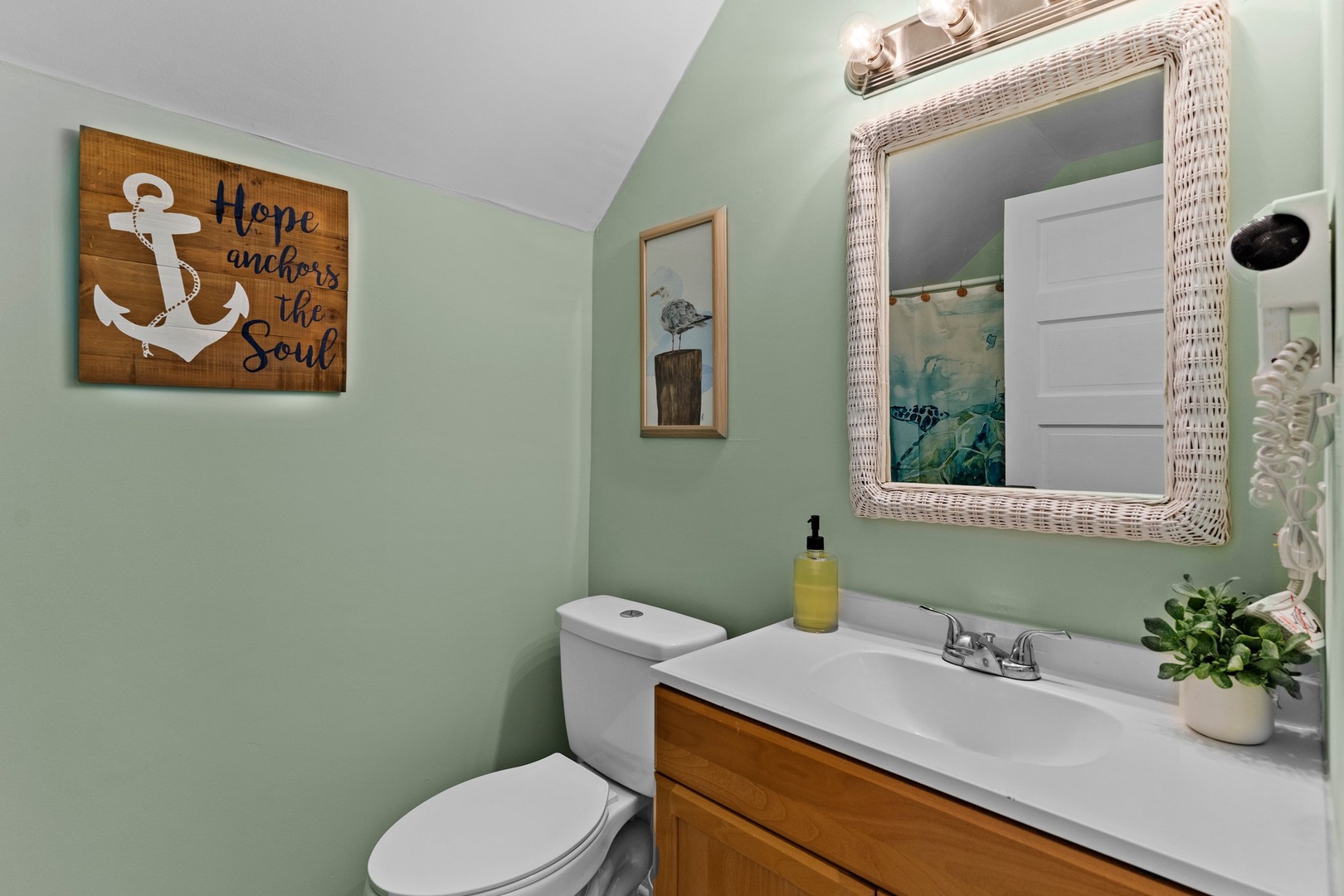 Your coastal-themed bathroom features soothing mint walls, charming nautical decor, and thoughtful touches like fresh greenery to make your stay feel like home.