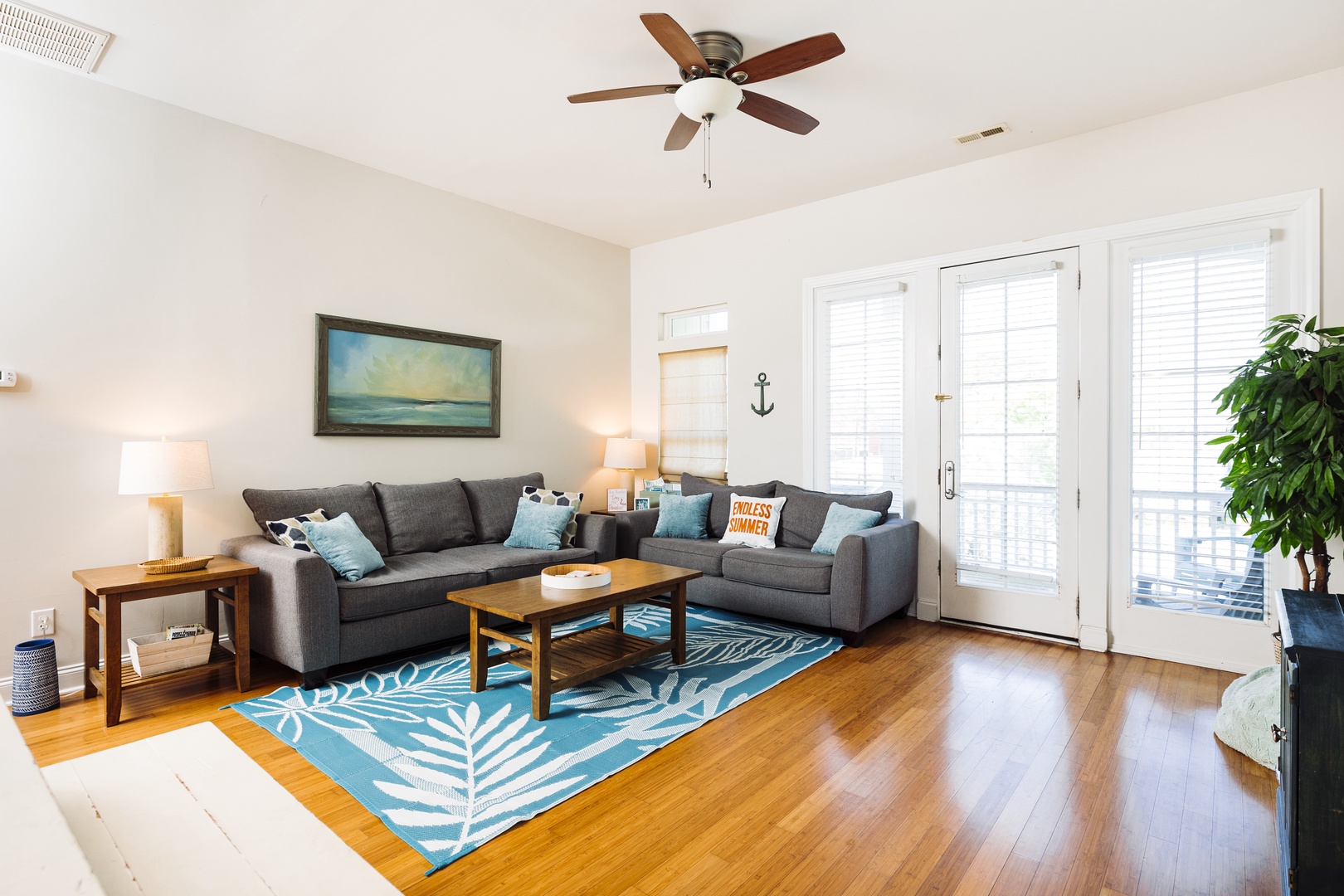 Relax in your spacious living room with cozy sectional seating, tropical-inspired decor, and gleaming hardwood floors beneath your feet.