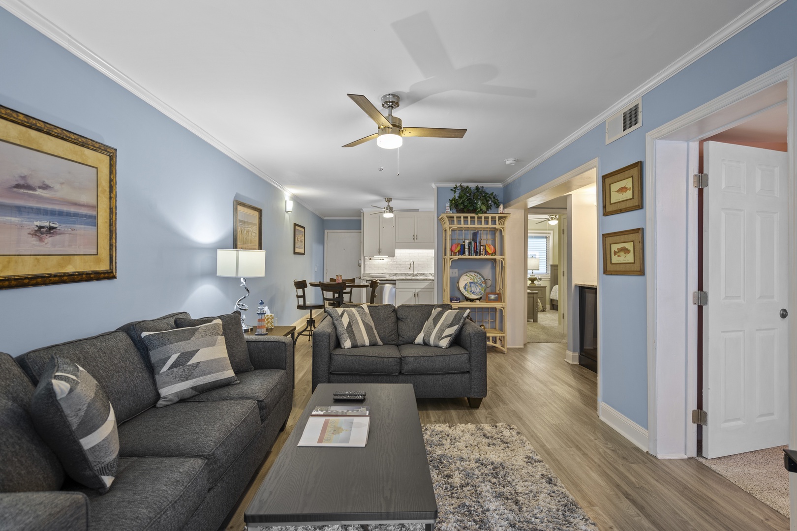 Sink into plush sofas in your bright living space, where coastal artwork and soft blue walls create the perfect atmosphere for relaxation.