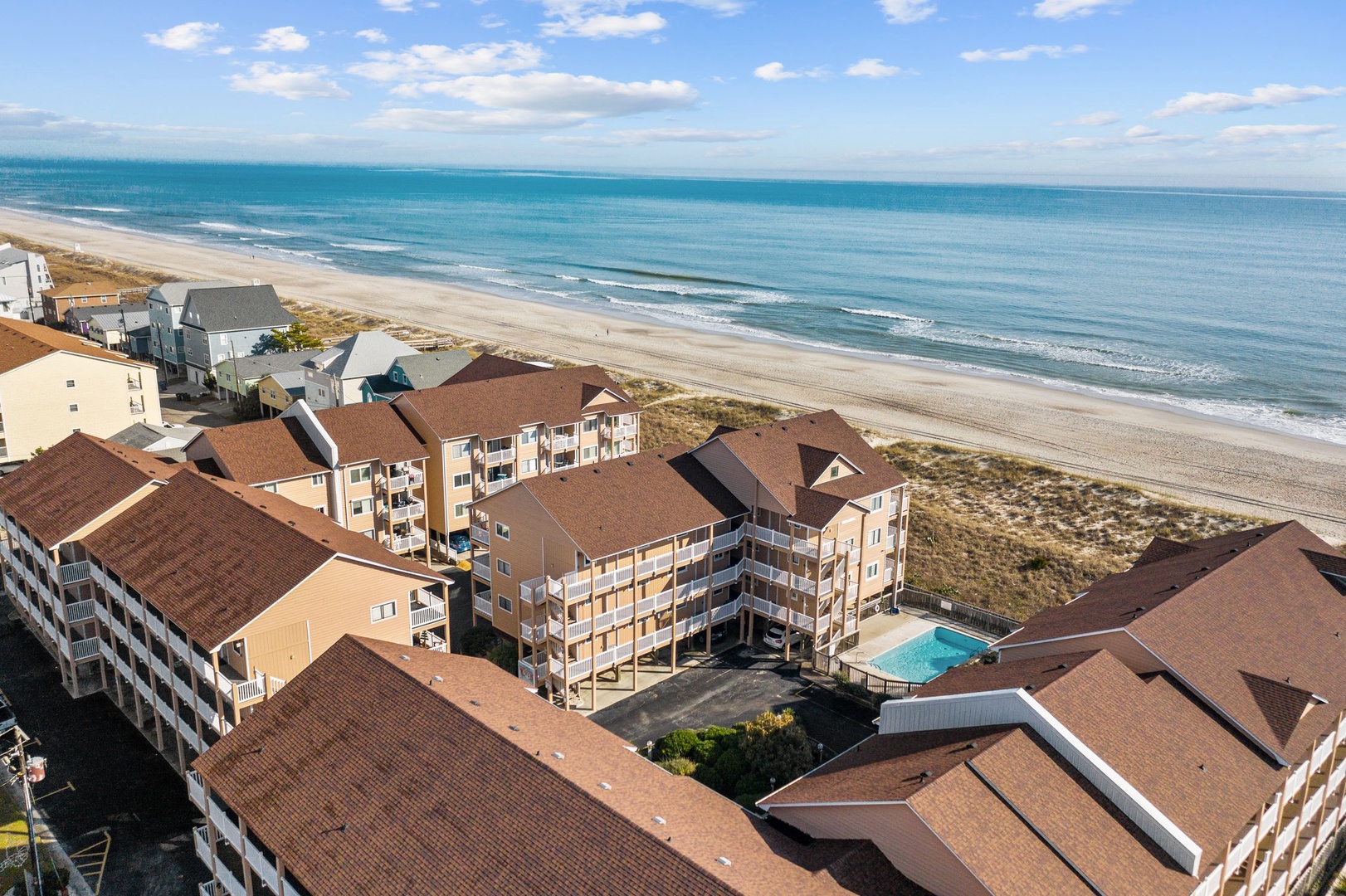 Beachfront resort complex with swimming pool situated directly on pristine sandy shores, offering convenient coastal access.