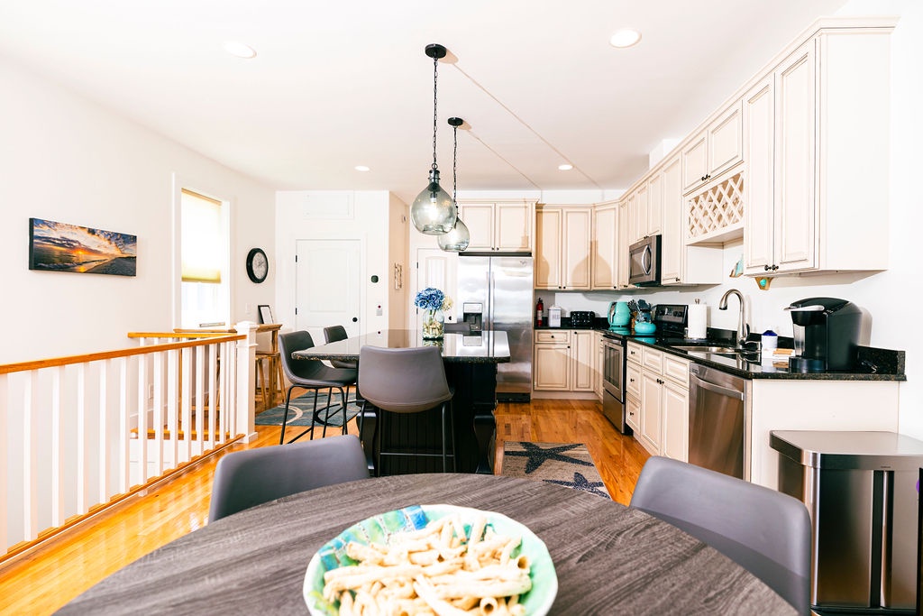 Your spacious kitchen and dining area invites memorable meals with elegant pendant lighting, granite counters, and warm wood floors.