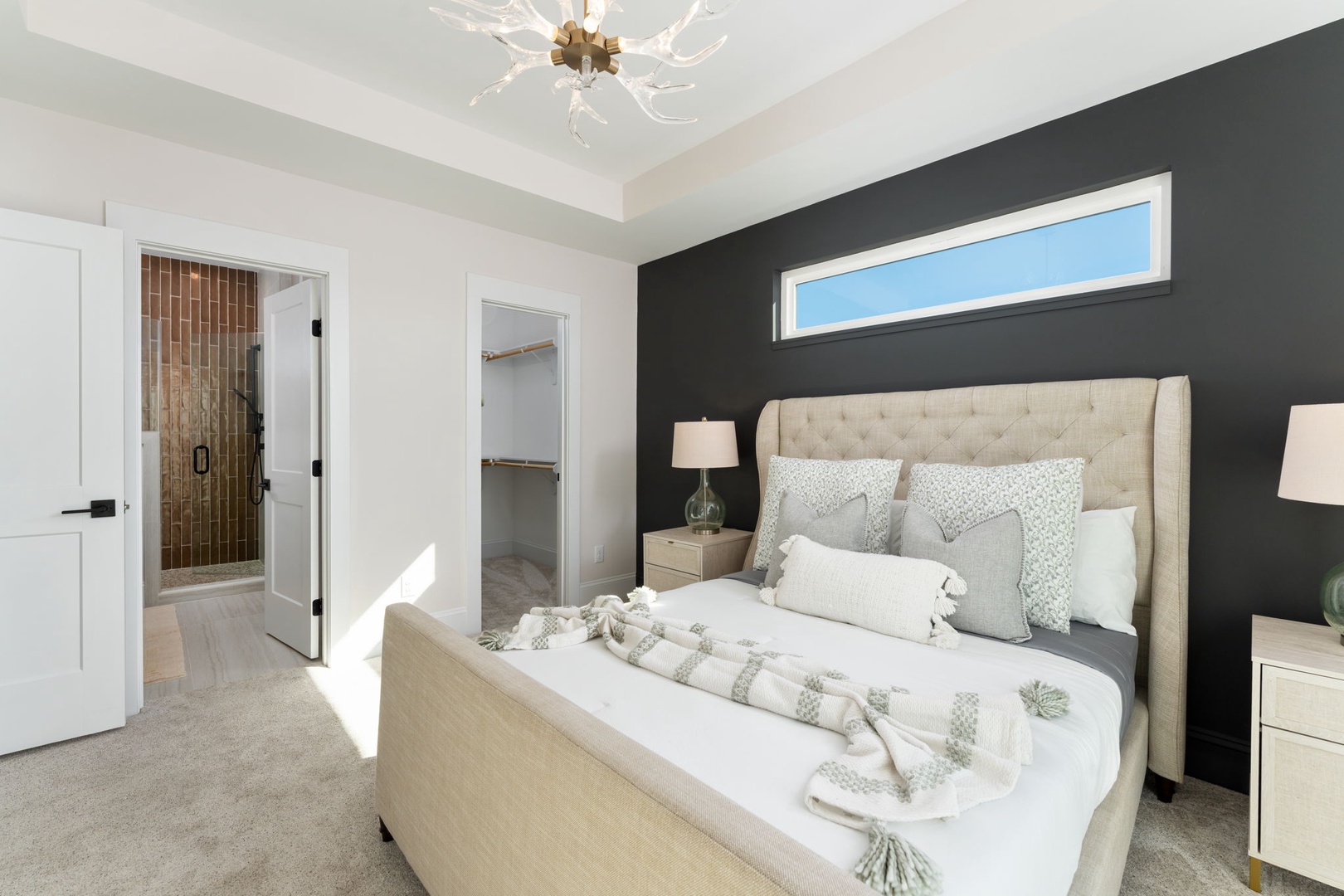 Sink into your luxurious master suite featuring a plush tufted headboard, elegant chandelier, and ensuite bathroom with stunning tile work.