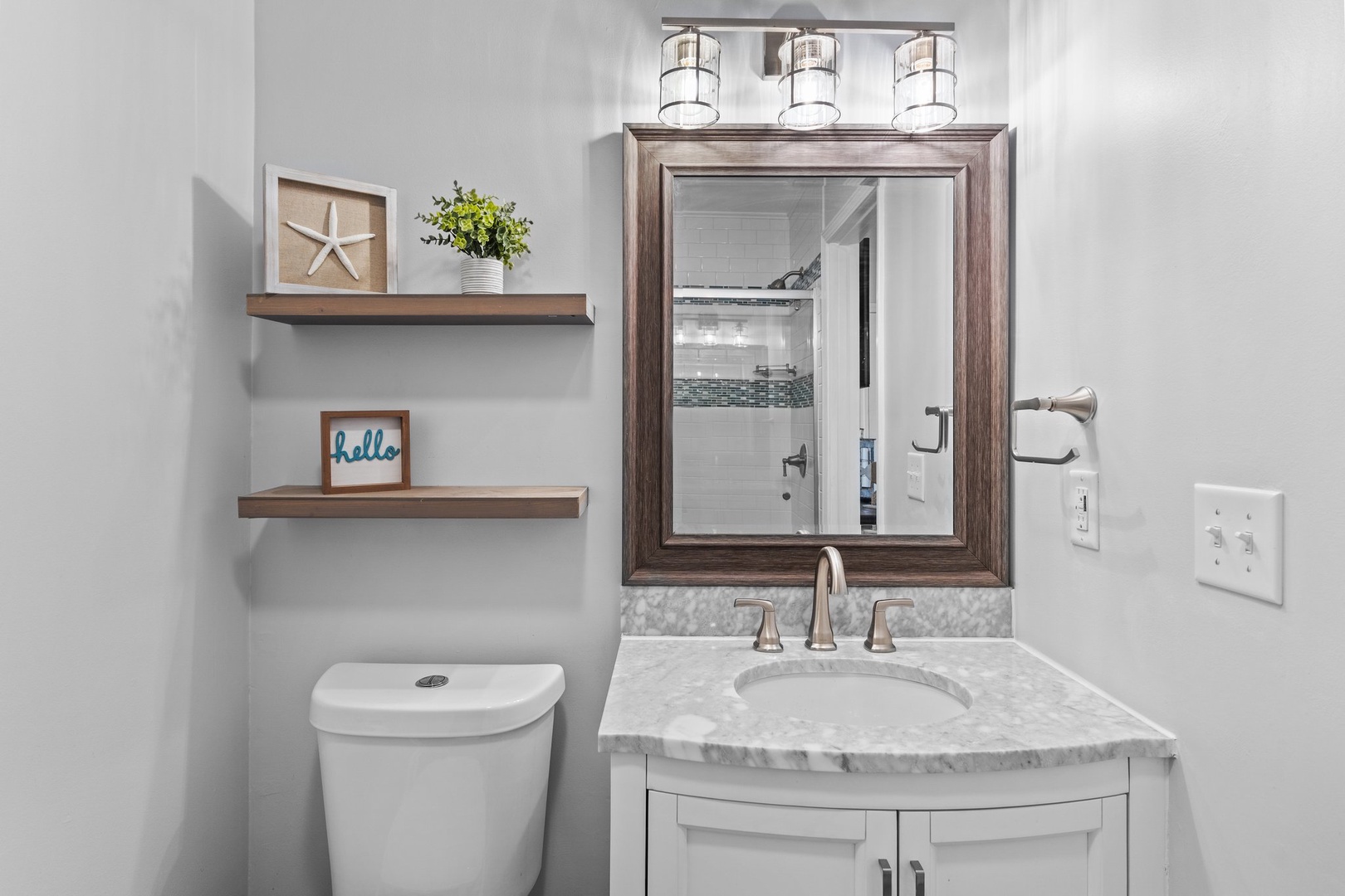 Your beautifully appointed bathroom combines coastal charm with modern elegance, featuring warm wood accents and marble surfaces for your comfort.