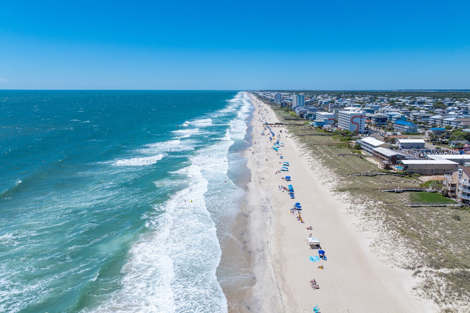 Aerial view of the property's beachfront location along pristine white sands and turquoise waters. The coastal setting places this vacation rental within easy reach of seaside relaxation.