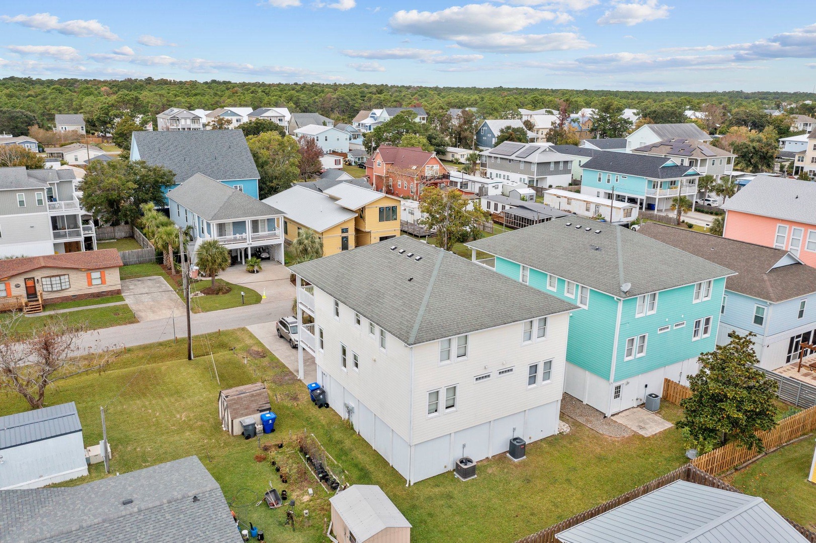 Aerial view of a charming coastal neighborhood with colorful beach houses nestled among mature trees.