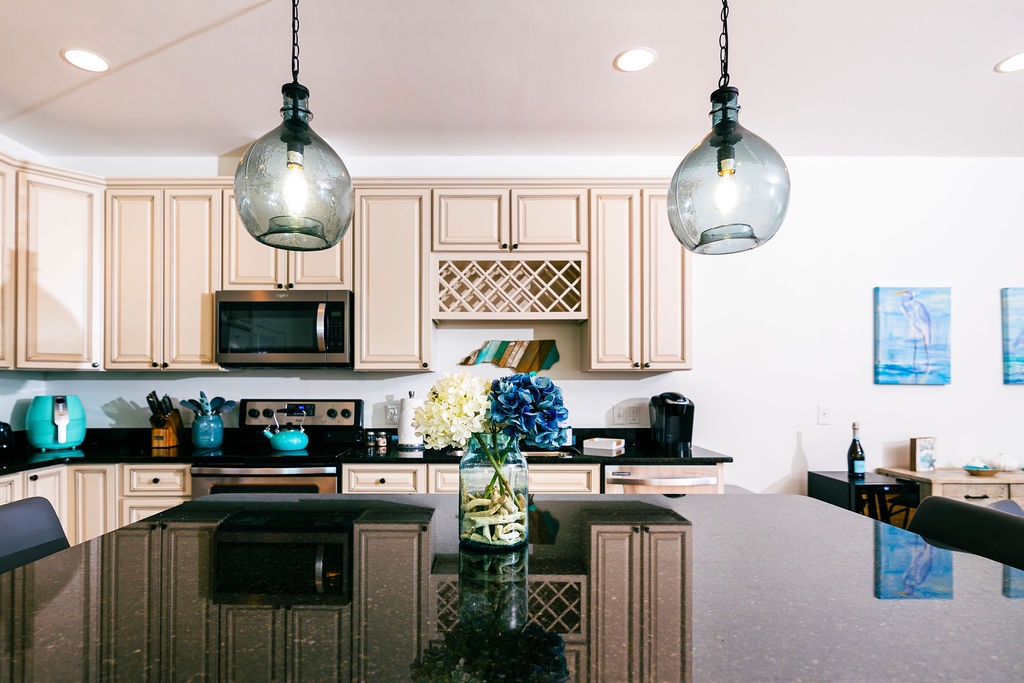Your gourmet kitchen awaits with granite counters, pendant lighting, and fresh flowers creating the perfect space for memorable meals.