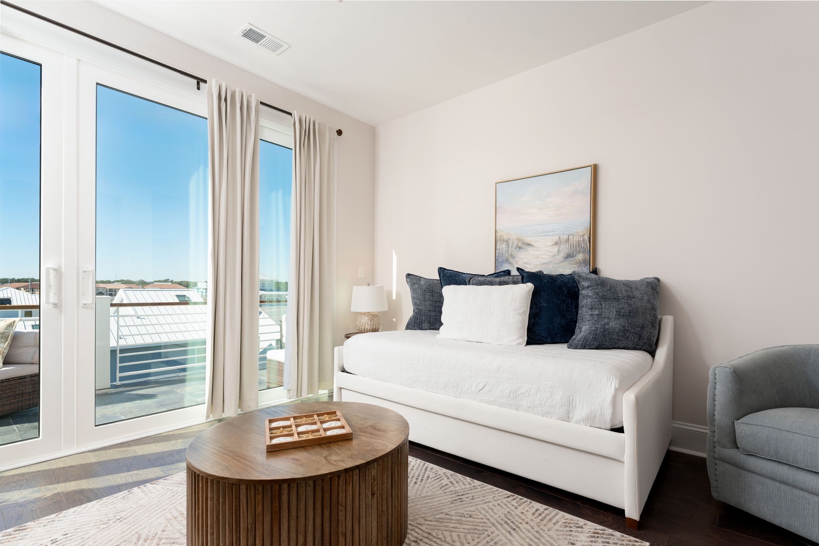 Bright living space with balcony views where you can unwind on the crisp white daybed surrounded by natural light.