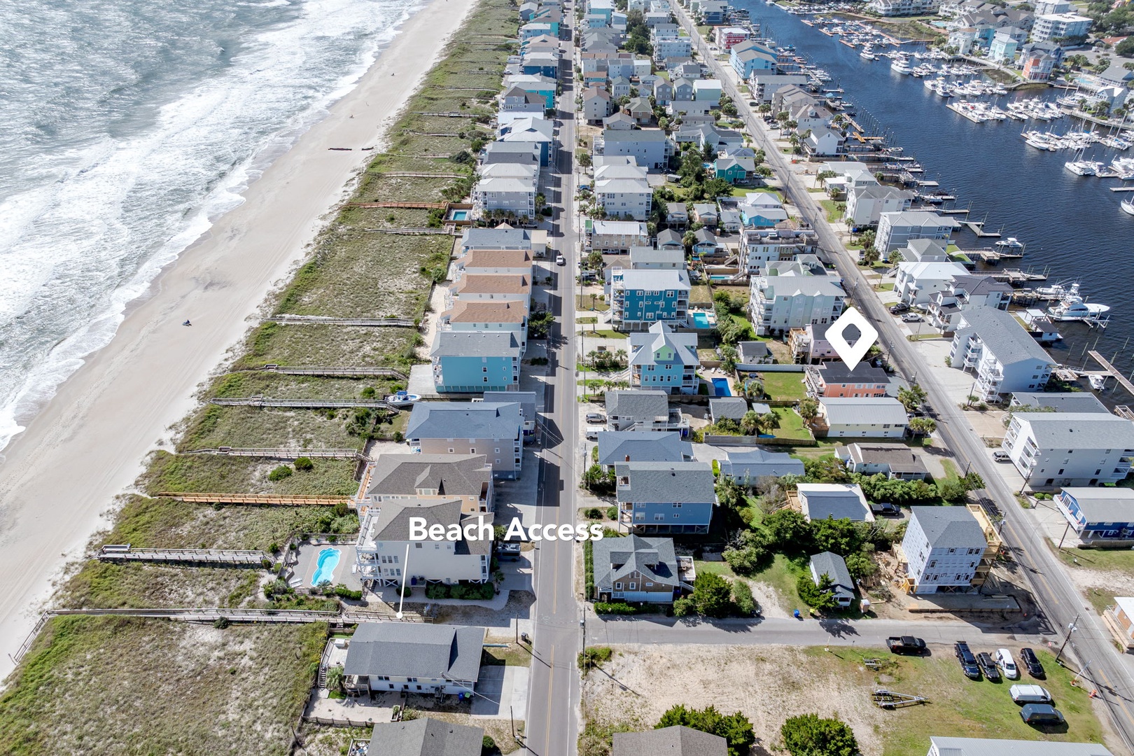 Aerial view of coastal community featuring beachfront homes with direct ocean access and nearby marina facilities.