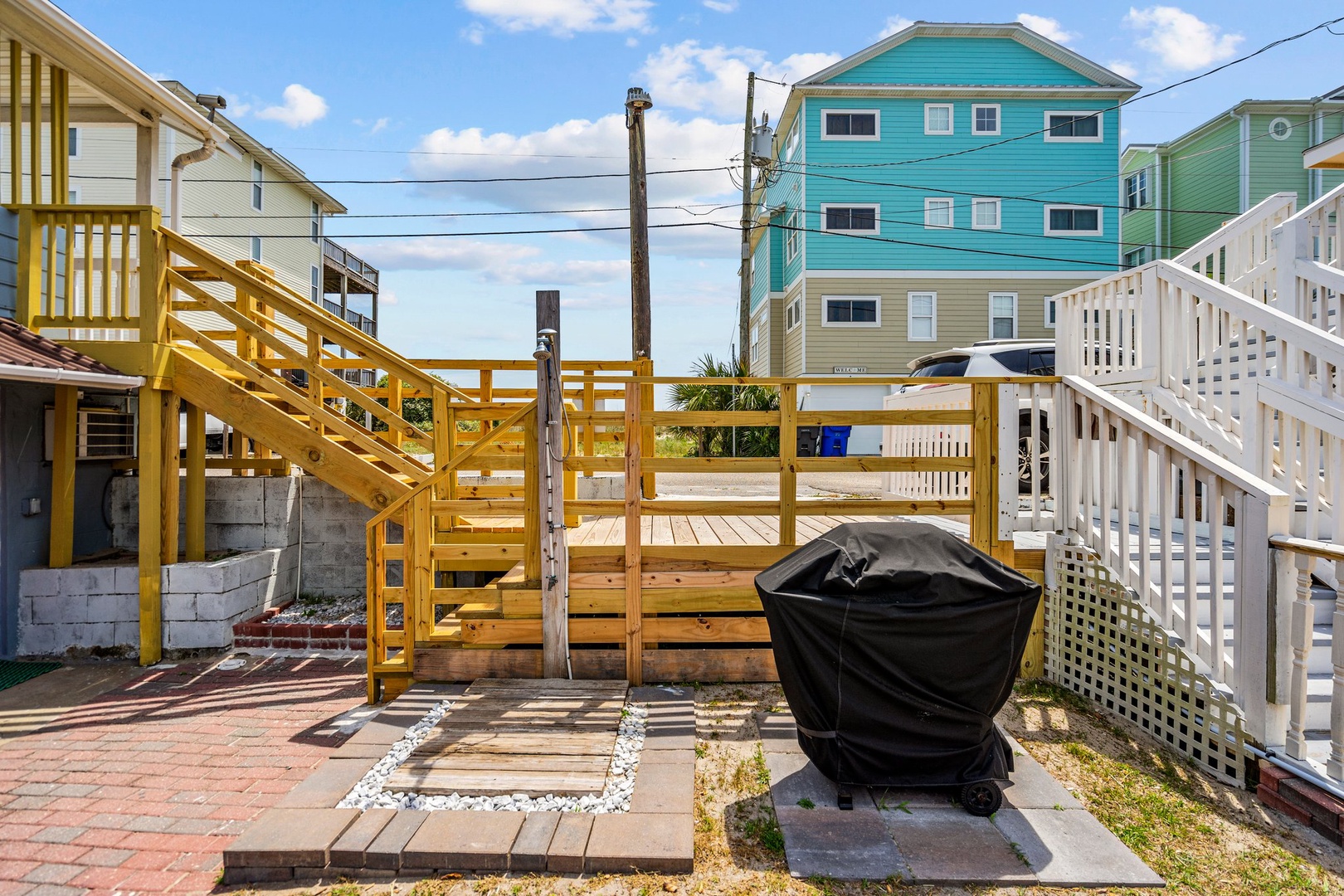 Your private deck features a covered grill, perfect for beachside barbecues with colorful coastal homes as your backdrop.