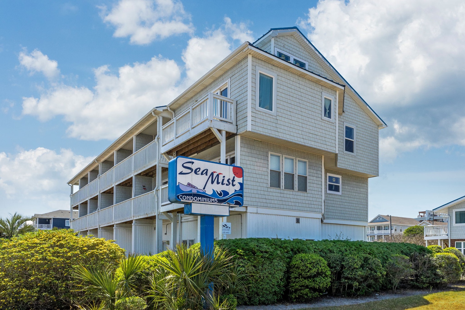 Sea Mist Condominiums offers coastal charm with gray-shingled architecture, private balconies, and lush tropical landscaping in a peaceful seaside neighborhood setting.