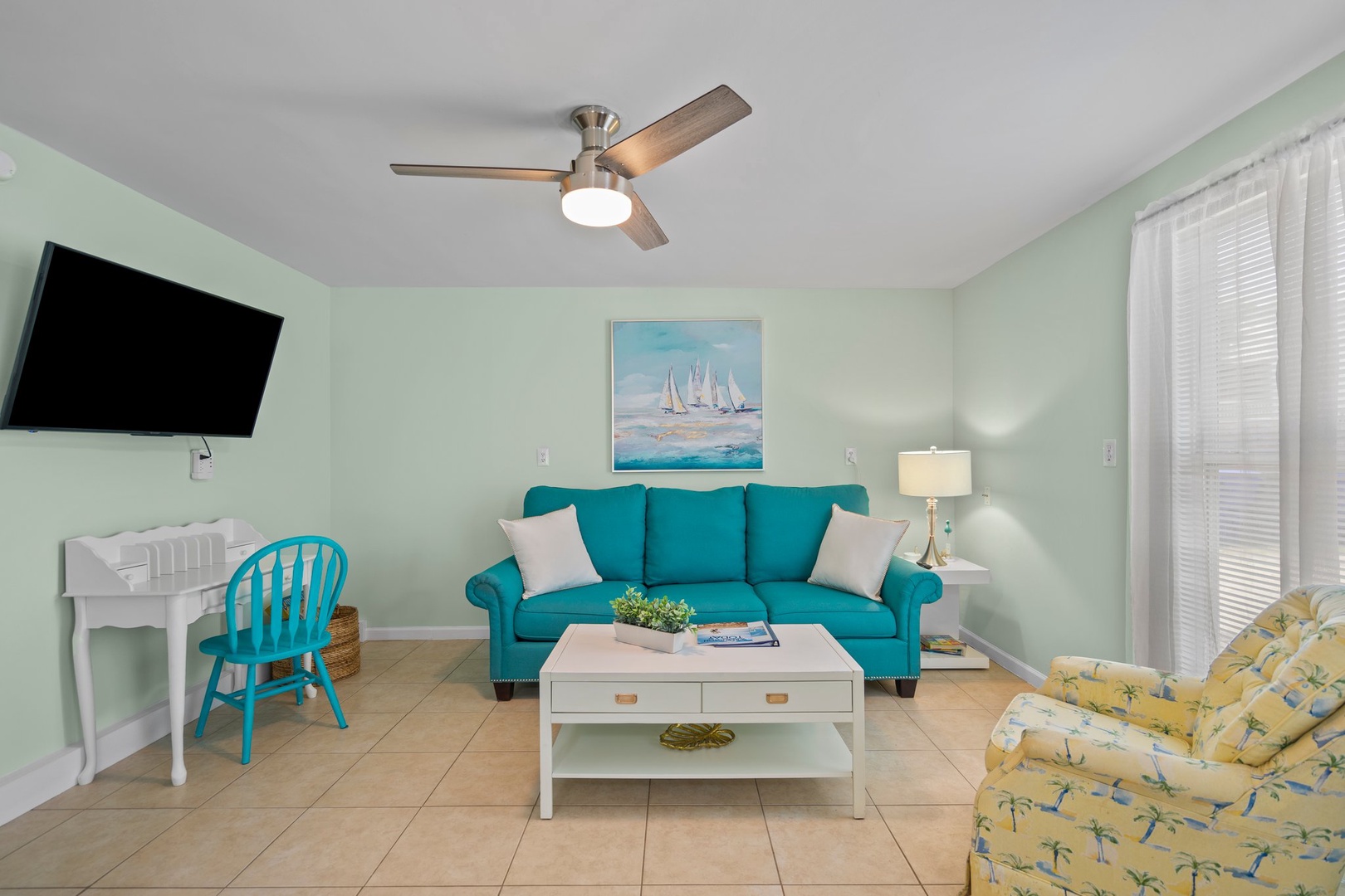 Sink into your coastal living room's turquoise sofa and enjoy the sea breeze from the ceiling fan above.
