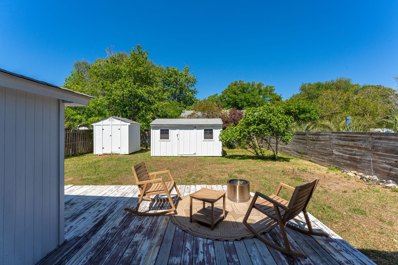 Relax on your private deck with teak chairs overlooking a spacious backyard, perfect for morning coffee or evening unwinding.
