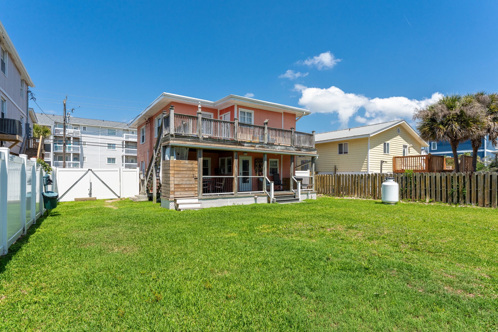 This charming beachside property features a spacious backyard with lush green lawn, perfect for outdoor gatherings and relaxation near the shore.