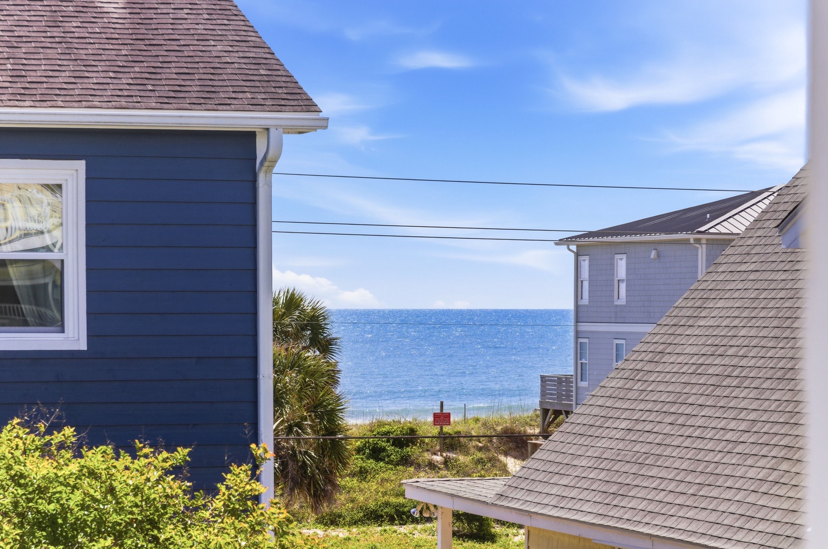 A coastal community tucked between beach cottages, where sparkling blue waters meet sandy dunes just steps from your front door.