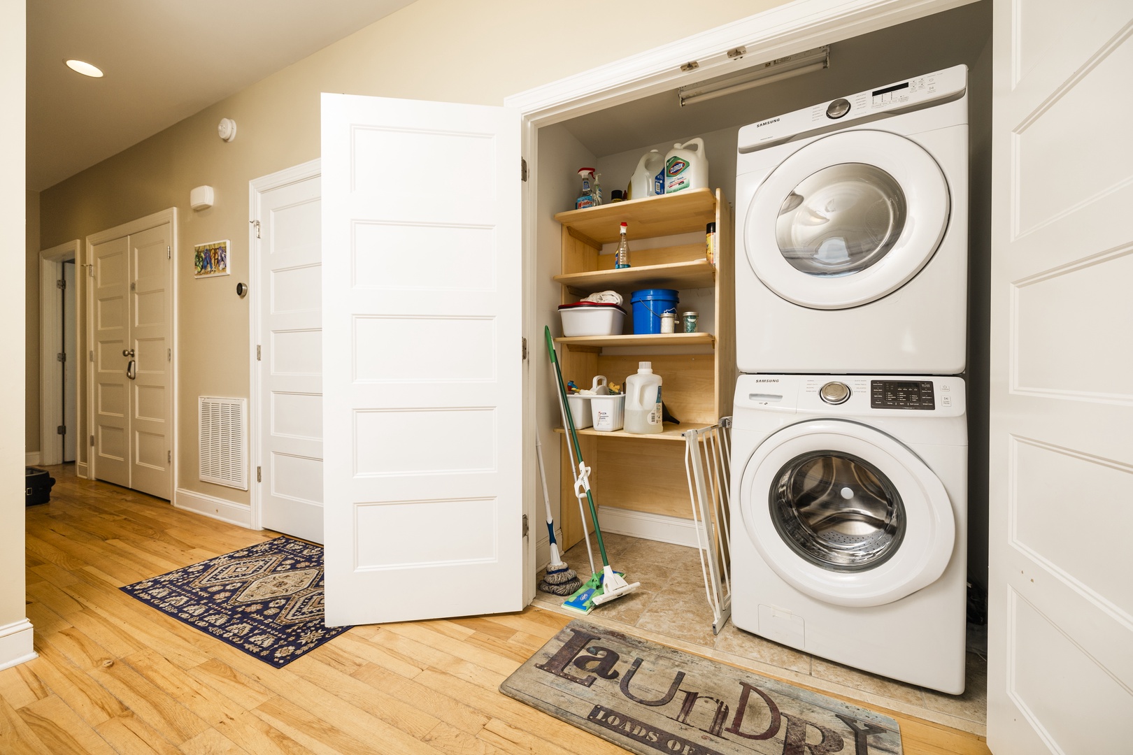 Your in-unit washer and dryer make extended stays effortless, with organized shelving and cleaning supplies tucked neatly in this bright hallway closet.