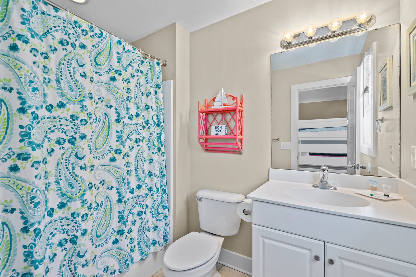 You'll love this bright bathroom with cheerful paisley shower curtain, Hollywood-style vanity lighting, and fresh white fixtures for your daily routine.