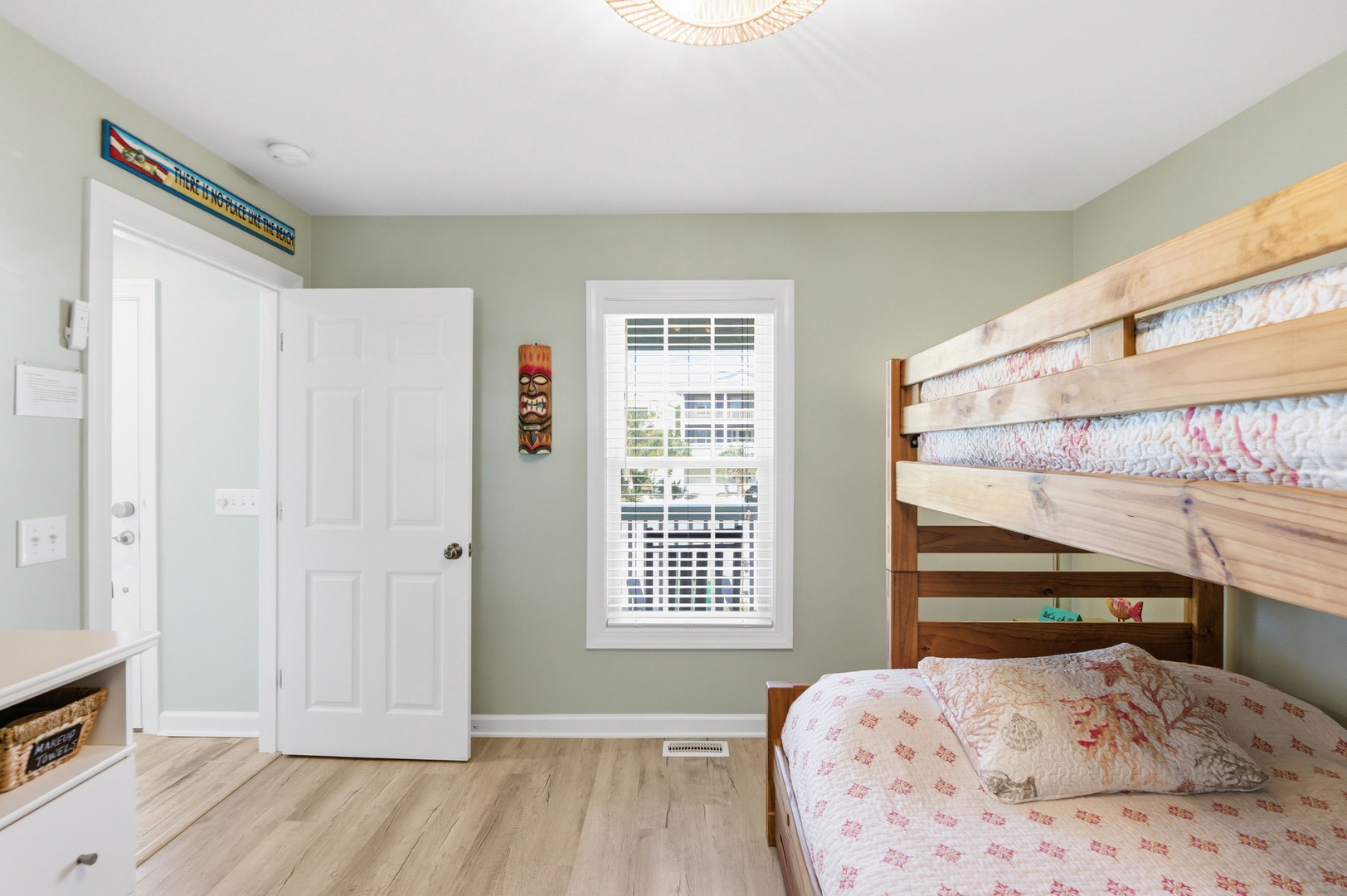 Your cozy bedroom features a sturdy wooden bunk bed dressed in soft, patterned linens—perfect for families or friends traveling together. Soft green walls and natural light create a peaceful retreat after a day of exploring.