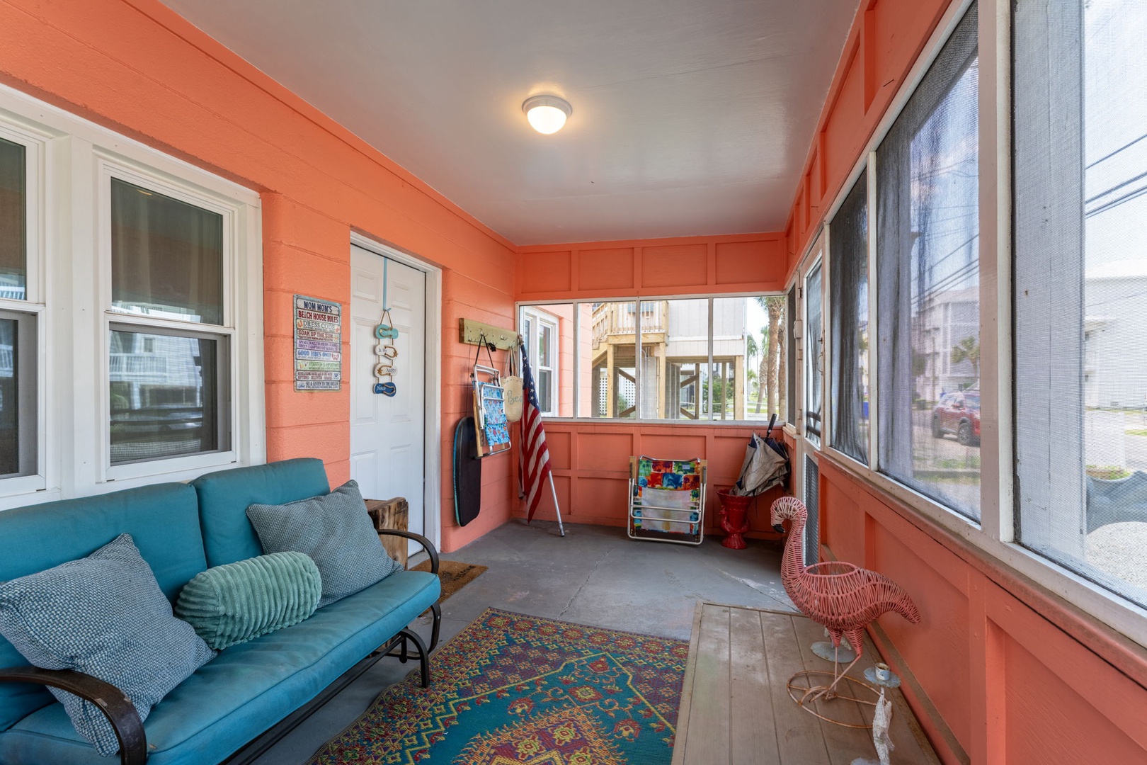 Step into your bright coral-colored sunroom where soft seating invites you to relax with a book or sip morning coffee while gazing at neighborhood views through screened windows.