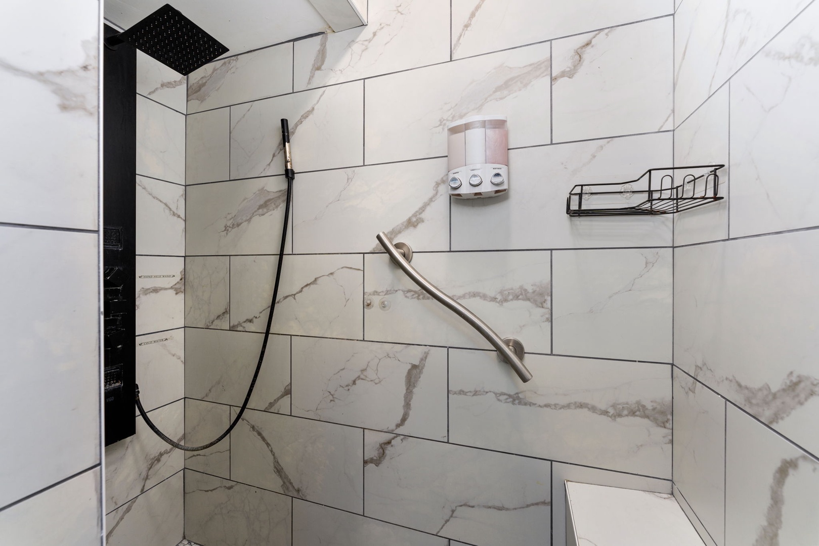 Step into your spa-like shower featuring elegant marble-look tile, a sleek rainfall showerhead, and convenient accessibility features designed for your comfort and ease.
