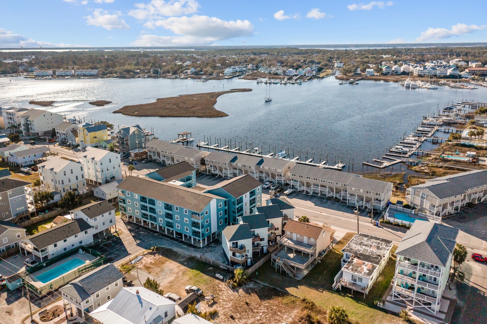 Coastal waterfront community featuring marina access and colorful residential properties near tranquil harbor waters.