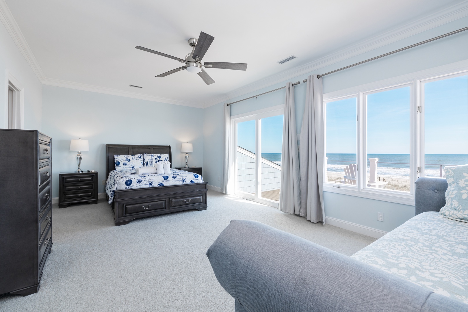 Wake up to stunning ocean views from your spacious bedroom with elegant dark wood furnishings and coastal charm.