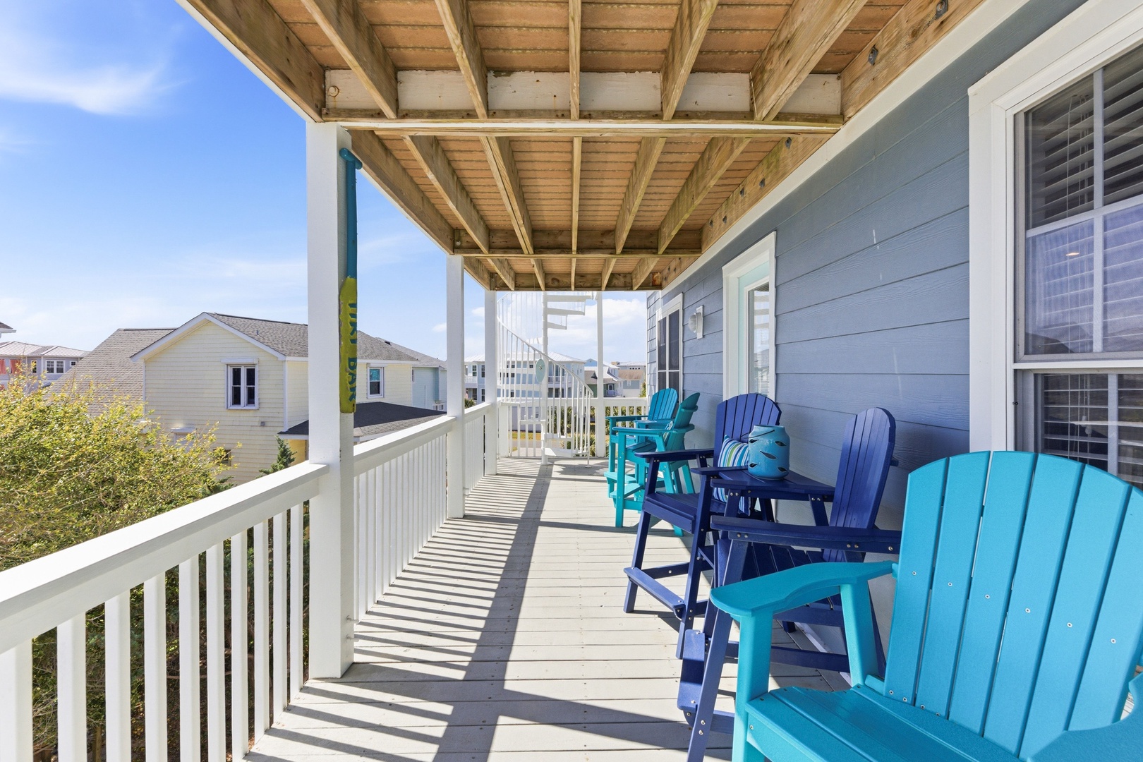 Covered deck with vibrant Adirondack chairs where you can relax and soak in the coastal breeze. Your morning coffee never looked so inviting.