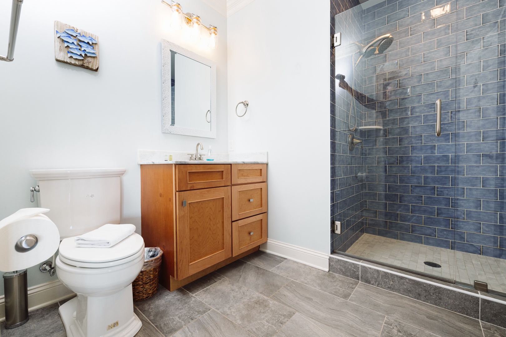 Step into your stylishly renovated bathroom with stunning blue subway tile shower and warm wood vanity for your comfort.