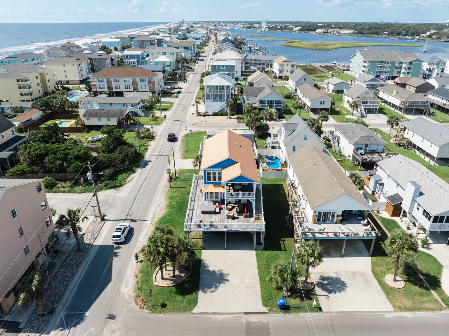 Aerial view of a vibrant beachfront community featuring colorful rental homes nestled between pristine beaches and peaceful waterways.