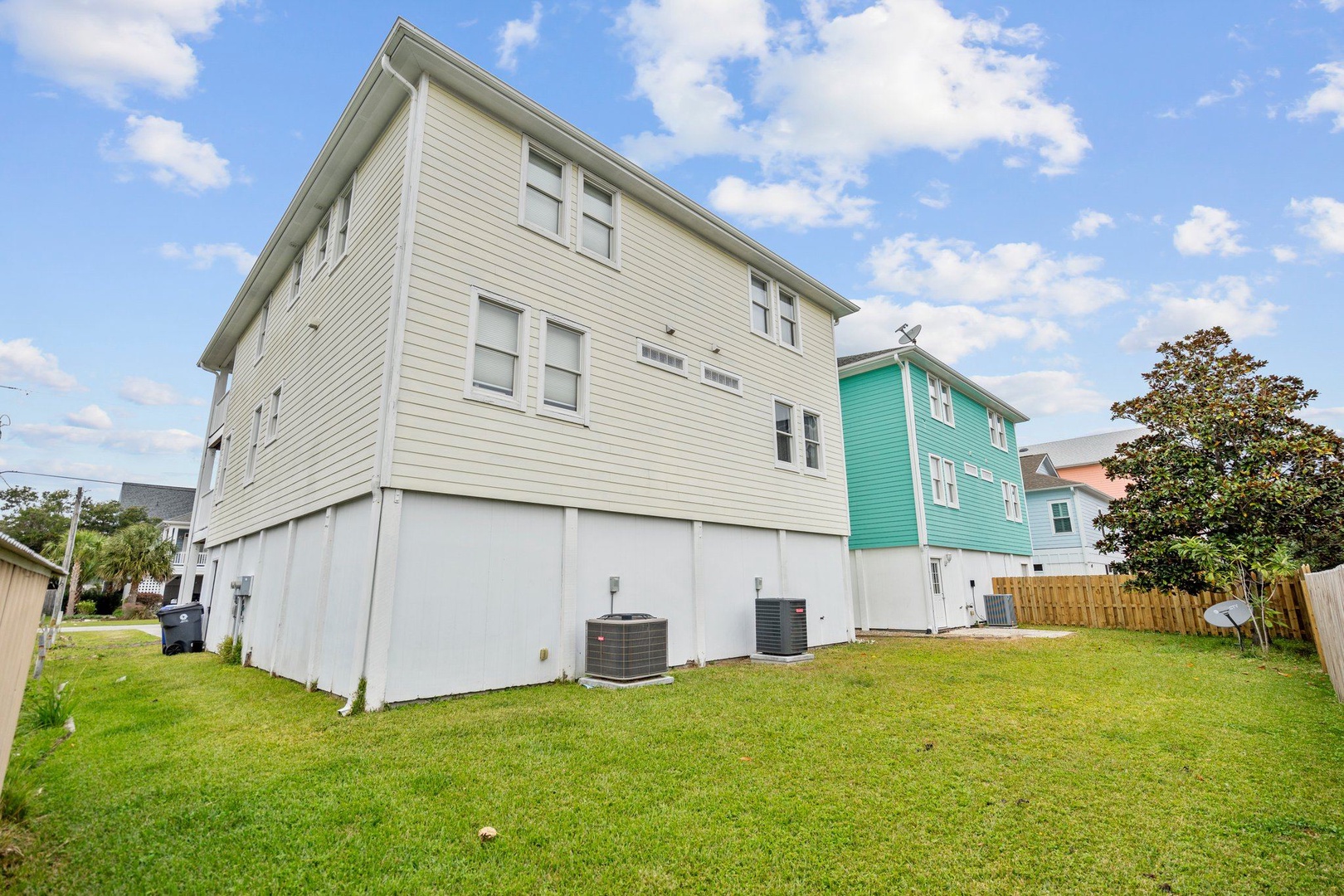 Modern coastal rental home with spacious yard in charming neighborhood setting with colorful nearby properties.