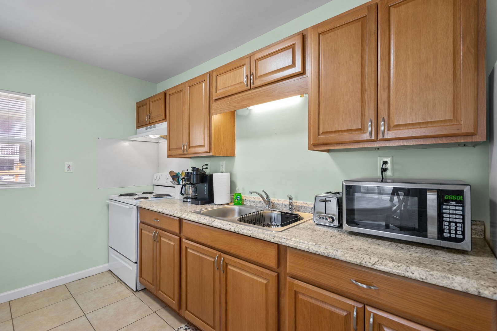 Your fully equipped kitchen features warm wood cabinets, granite countertops, and modern appliances including microwave and coffee maker for convenient home-style cooking.