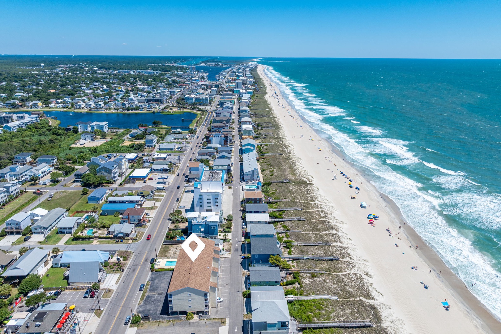 This coastal vacation community features a pristine sandy beach with direct ocean access, surrounded by residential neighborhoods and local amenities, all within a short distance of the property.
