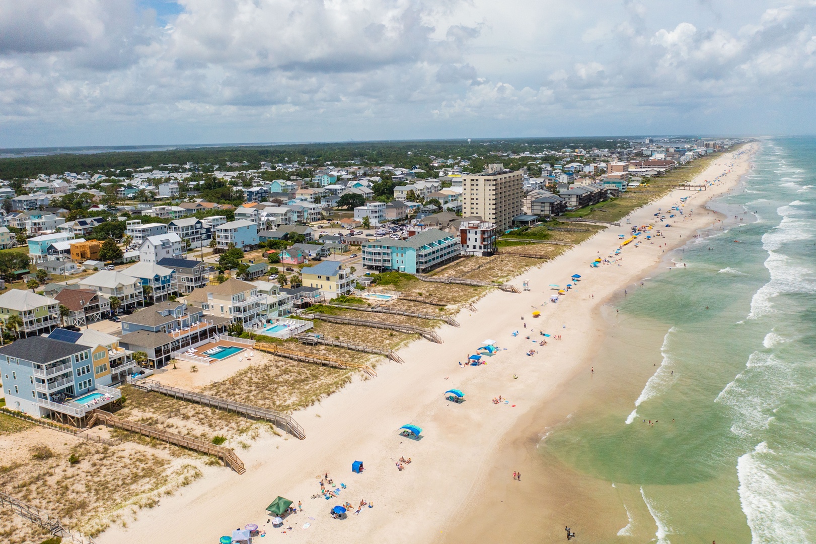 Aerial view of beachfront community with pristine sandy shores and turquoise waters stretching along the coastline.