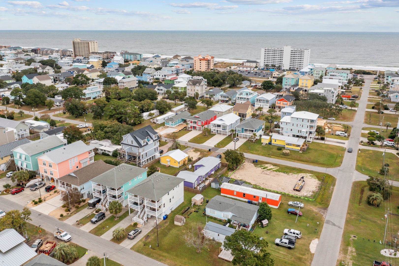 Aerial view of a vibrant coastal community with colorful beach houses, high-rise condos, and direct ocean access.