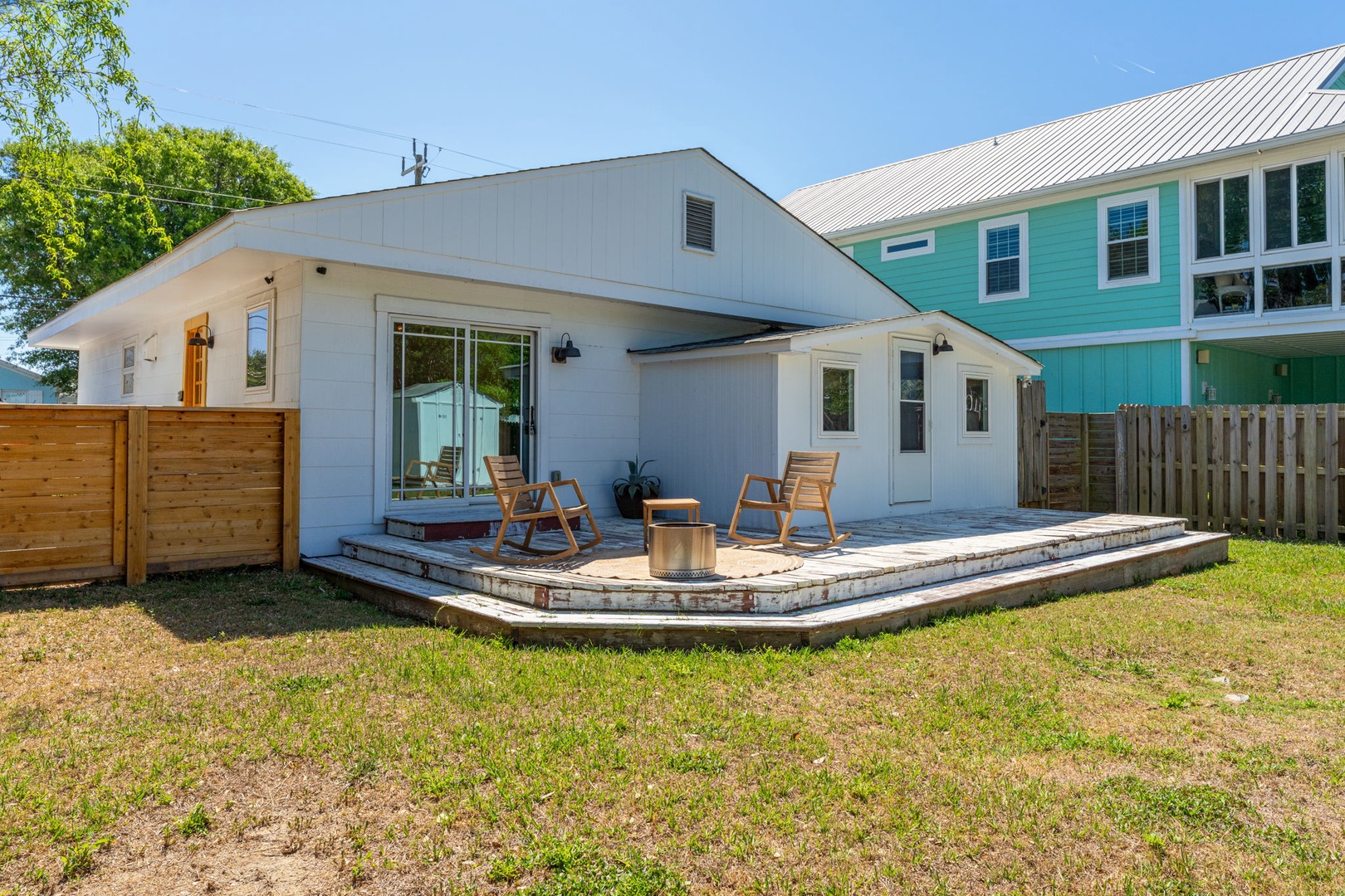Modern rental property with private deck featuring outdoor seating and distinctive metal roofing in residential neighborhood.