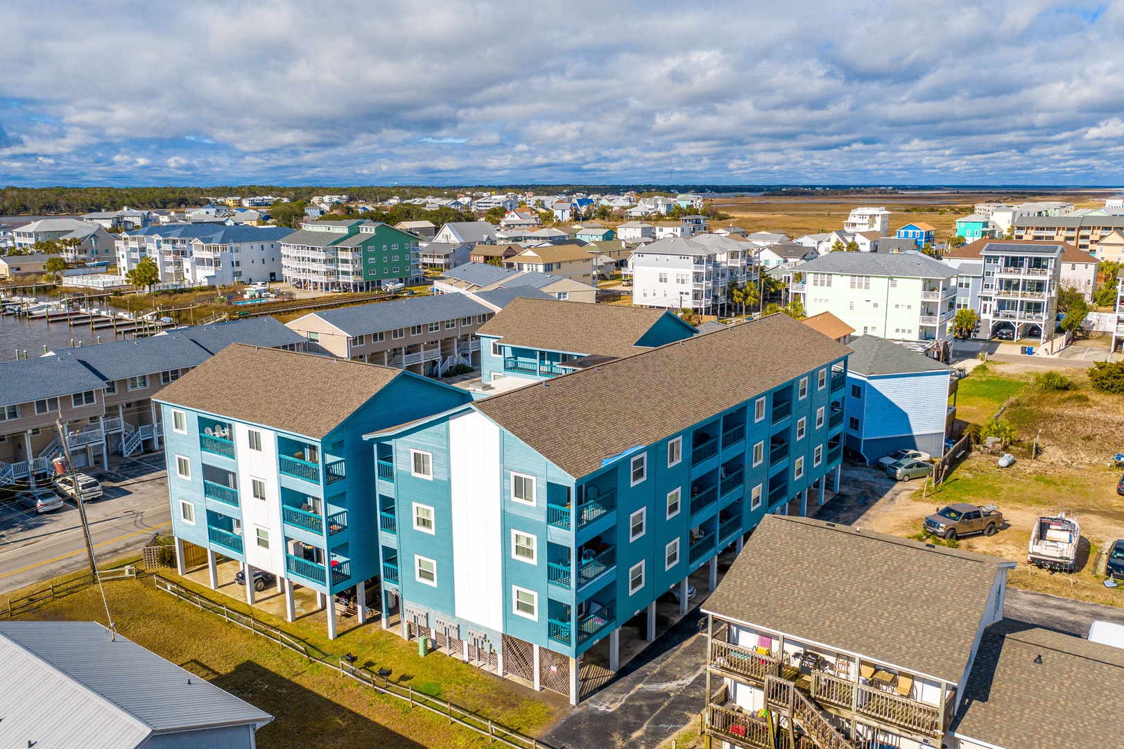 Aerial view of a coastal vacation rental community featuring distinctive blue and white buildings surrounded by beach town charm.